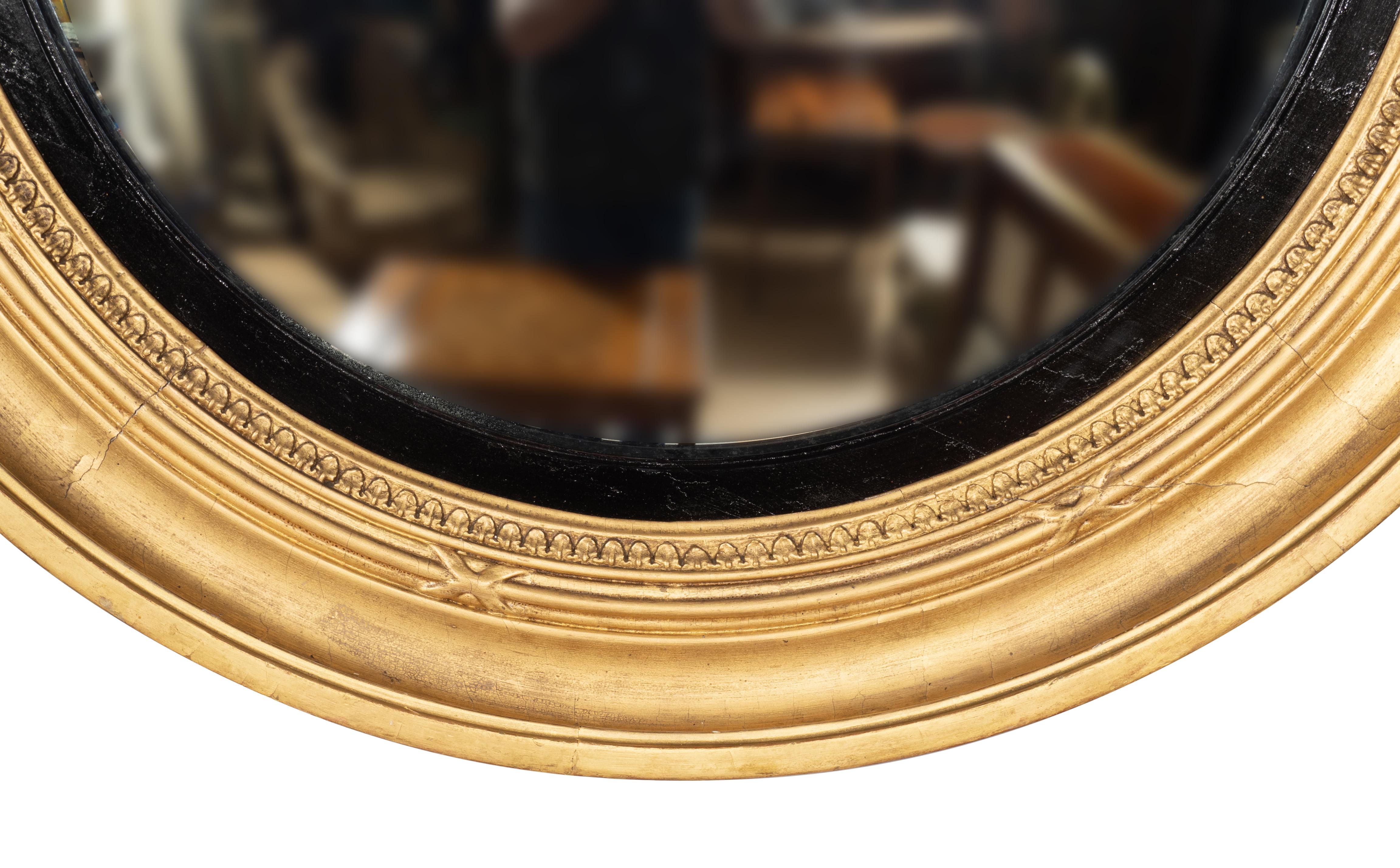 Large size with inner convex glass and ebonized inner ring and giltwood frame. The frame with carved leaf tip and fasces decoration.