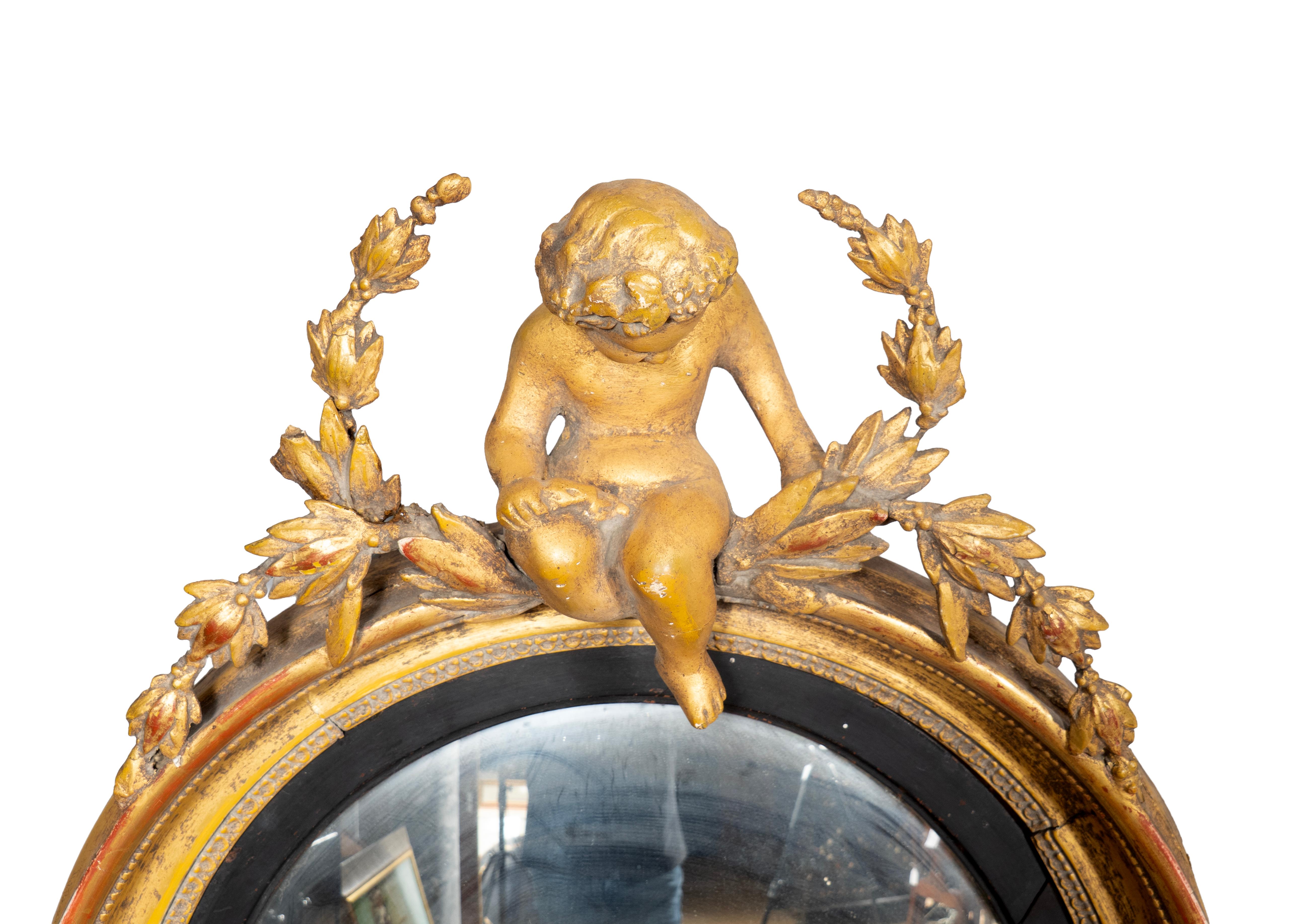 With putti and laurel leaf wreath over a convex mirror plate with ebonized border. Two candle arms.
