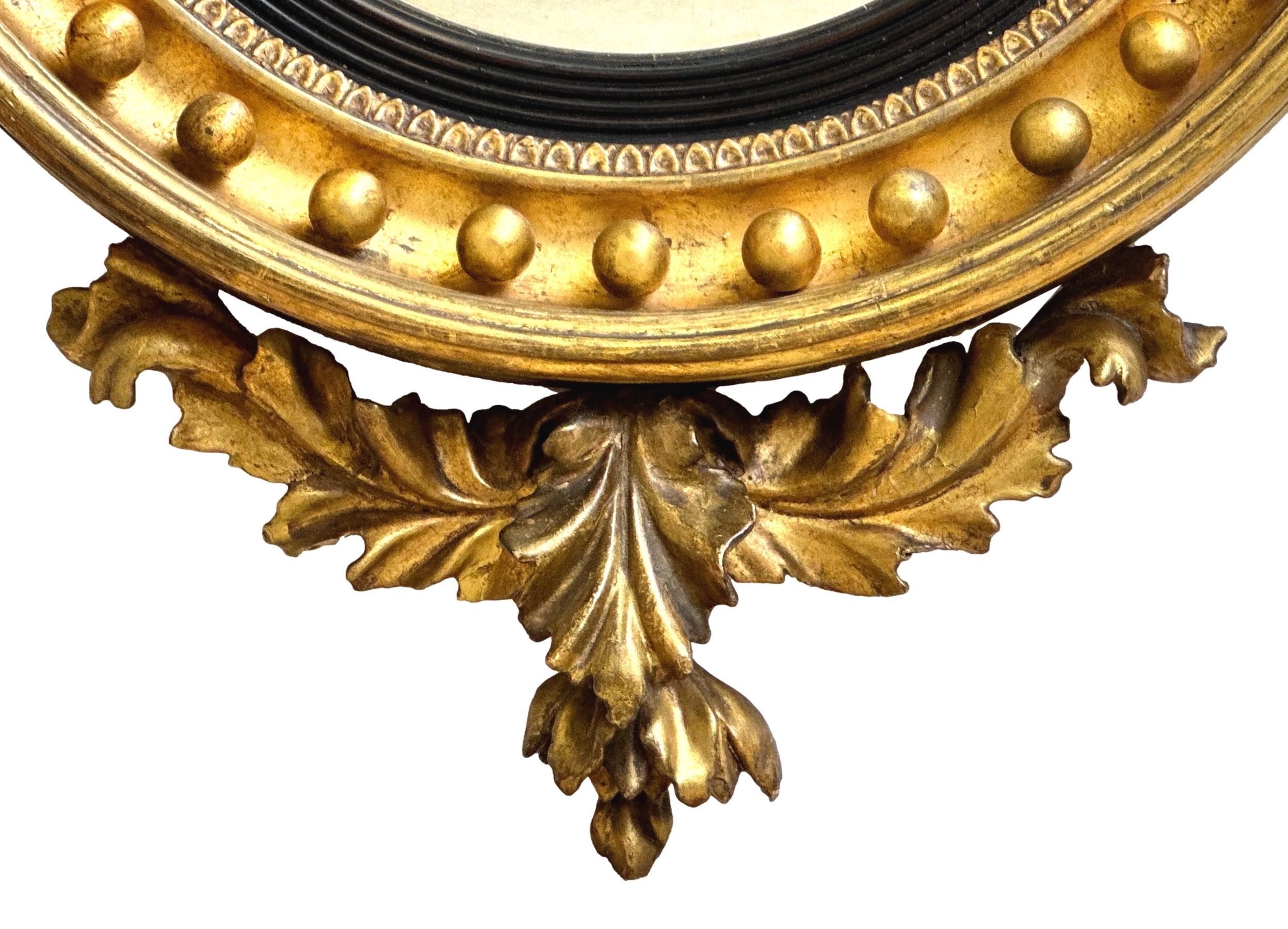 A fine Regency Period Giltwood Circular Convex Mirror, Surmounted With Attractive Stylised Dolphin Set Upon Rocks And Foliage To Top, Above Moulded Giltwood Concave Frame With Gilt Ball Border, Flanked By Elegant Original Candle Arms To Each Side