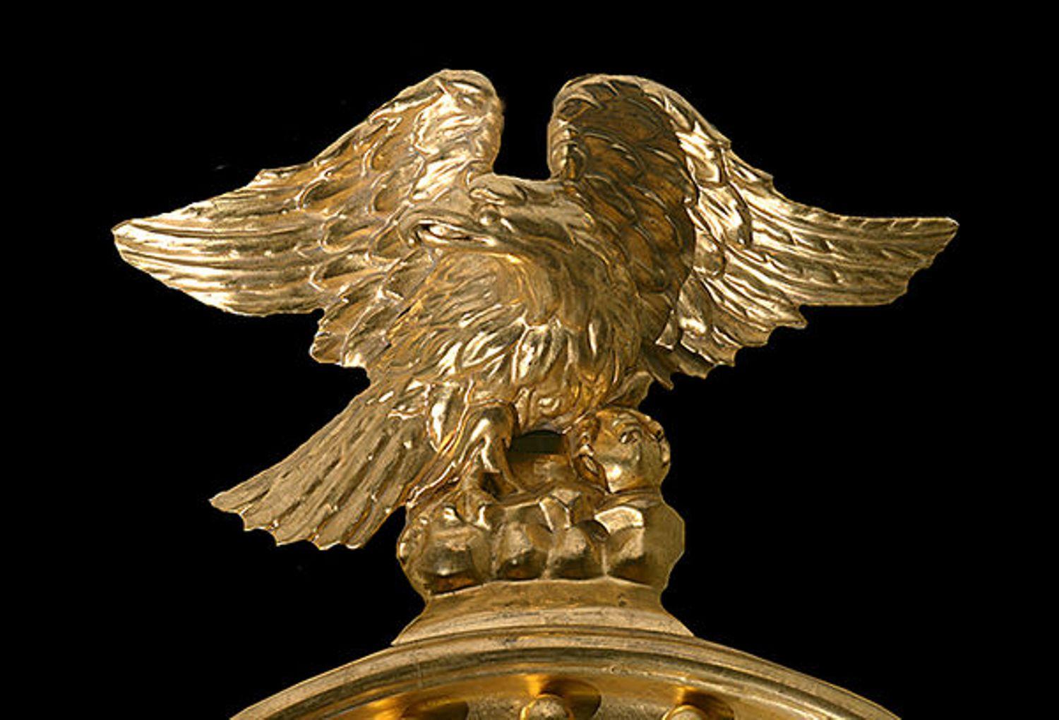 The convex mirror plate in a circular giltwood frame with gilt ball decoration and an ebonized slip.

A eagle surmounted to the top and an apron with a double layer of folate carving below.
