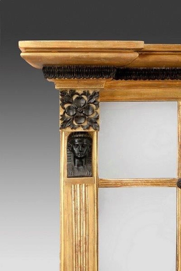 This attractive mirror retains all its original plates including the bevelled central plate and the six long and four square mirrors which surround it. The gilt frame has a stepped cornice edged with a bronze egg-and-dart moulding. The sides consist