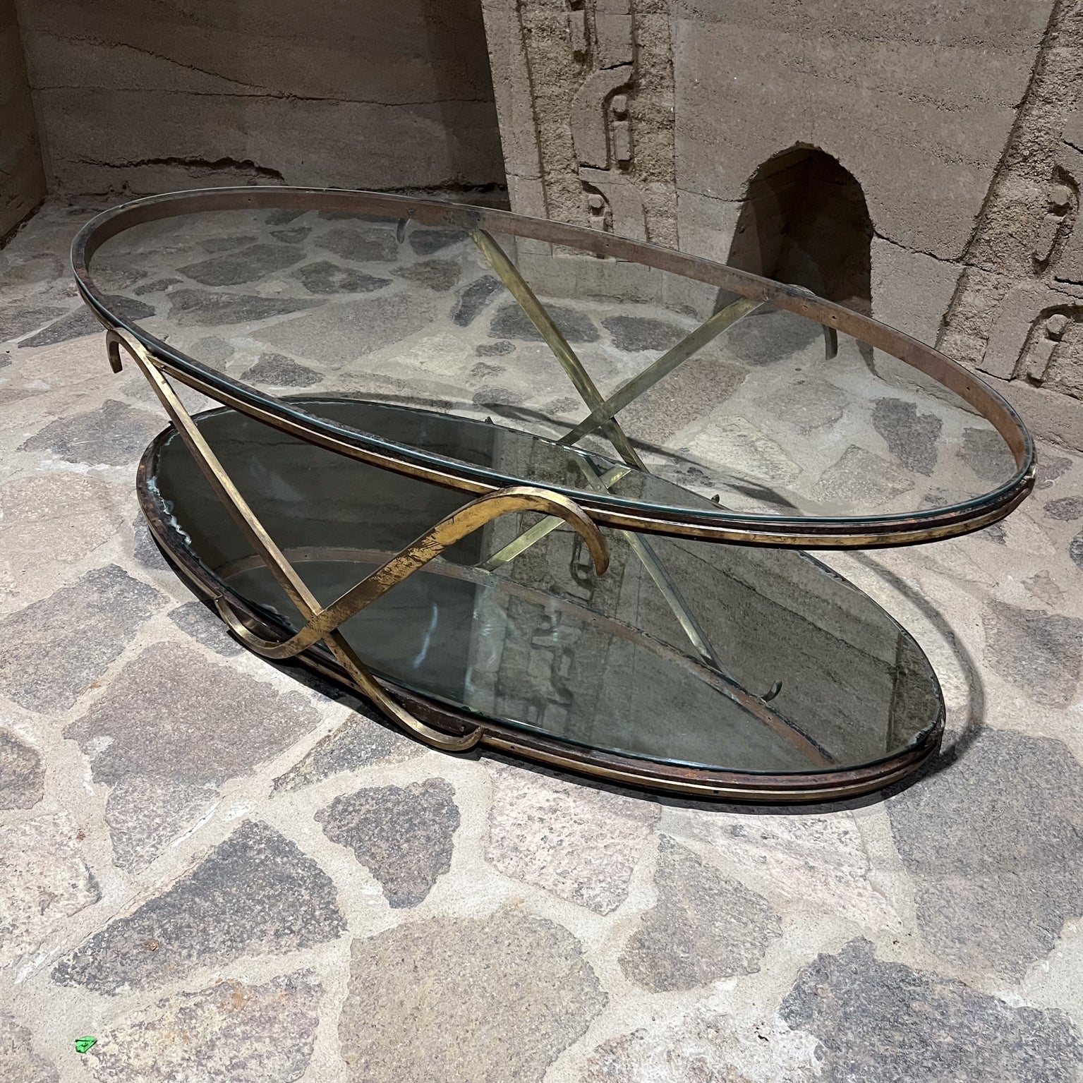Sculptural Tiered Coffee Table Mexico circa 1950s
Iron frame with Brass X oval mirrored Glass
Unmarked attribution Arturo Pani 
16 h x 51.13 long x 24.5 w
Original preowned vintage condition.
Original patina. Scuffs present.
Bottom mirror original