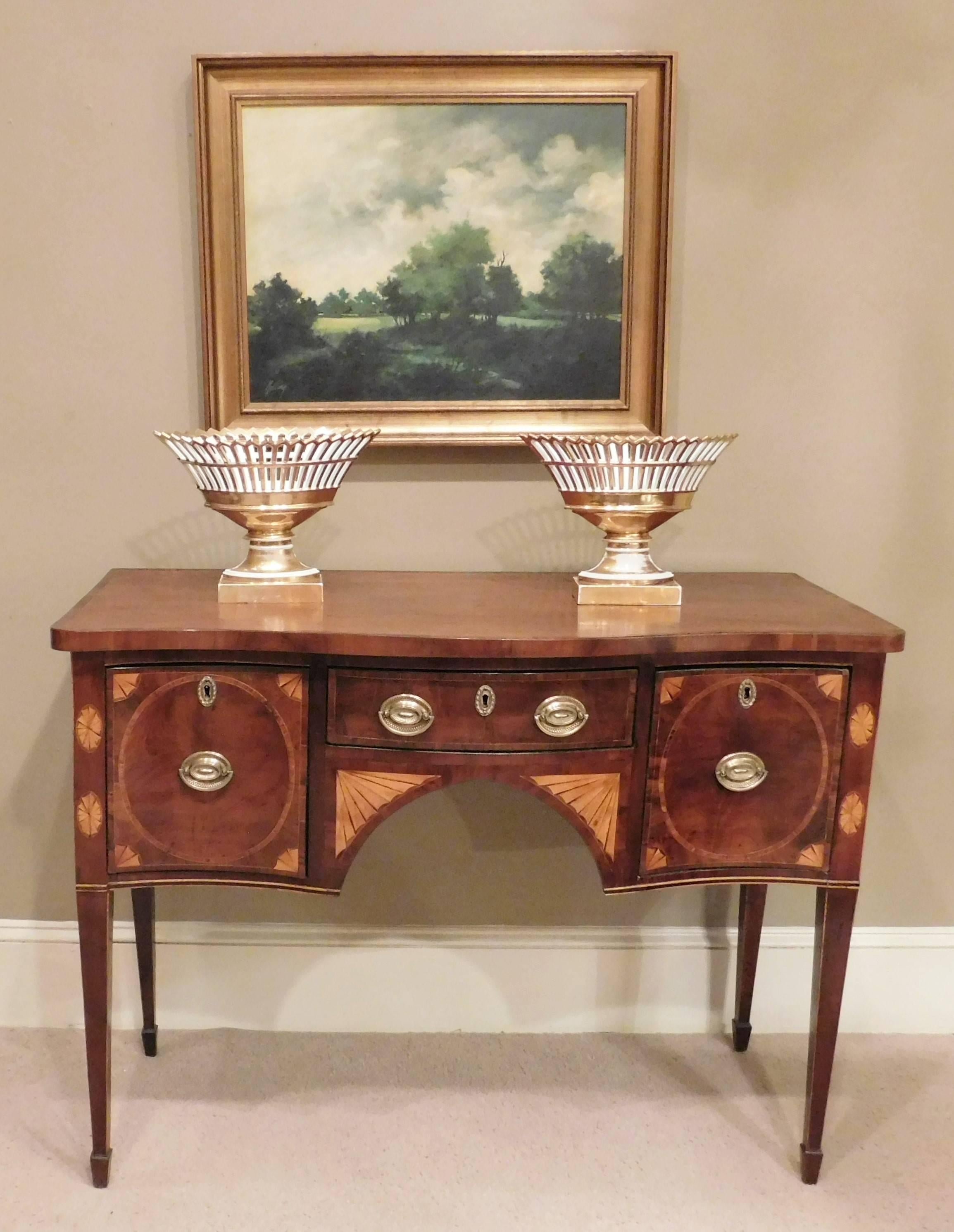 Mahogany George III sideboard with satinwood inlay and English oak secondary wood. Consists of one center drawer and two deep end drawers. Banded top and spade feet. Brass hardware are old replacements.