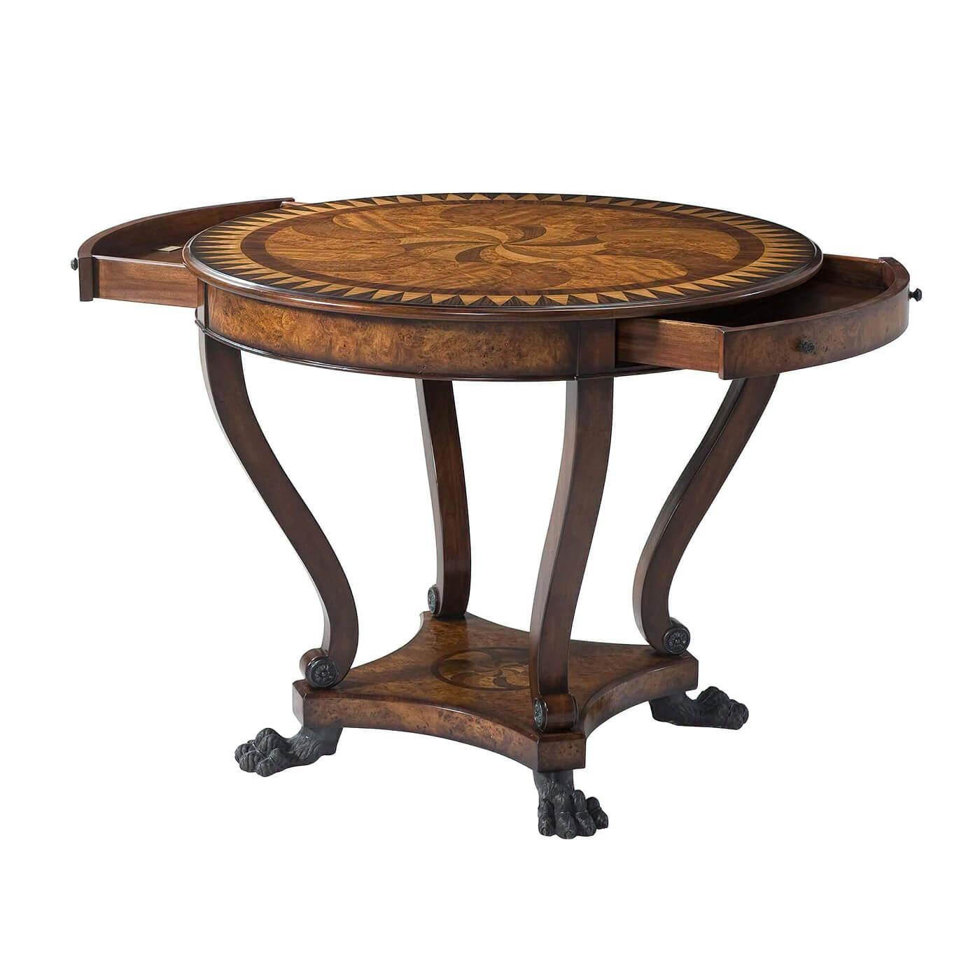 A Regency style marquetry hand-inlaid center table, the circular top with swirling hand inlay in rosewood and burl veneers with sunburst parquetry crossbanding, above two bowed frieze drawers, on inswept supports with scroll feet applied with brass