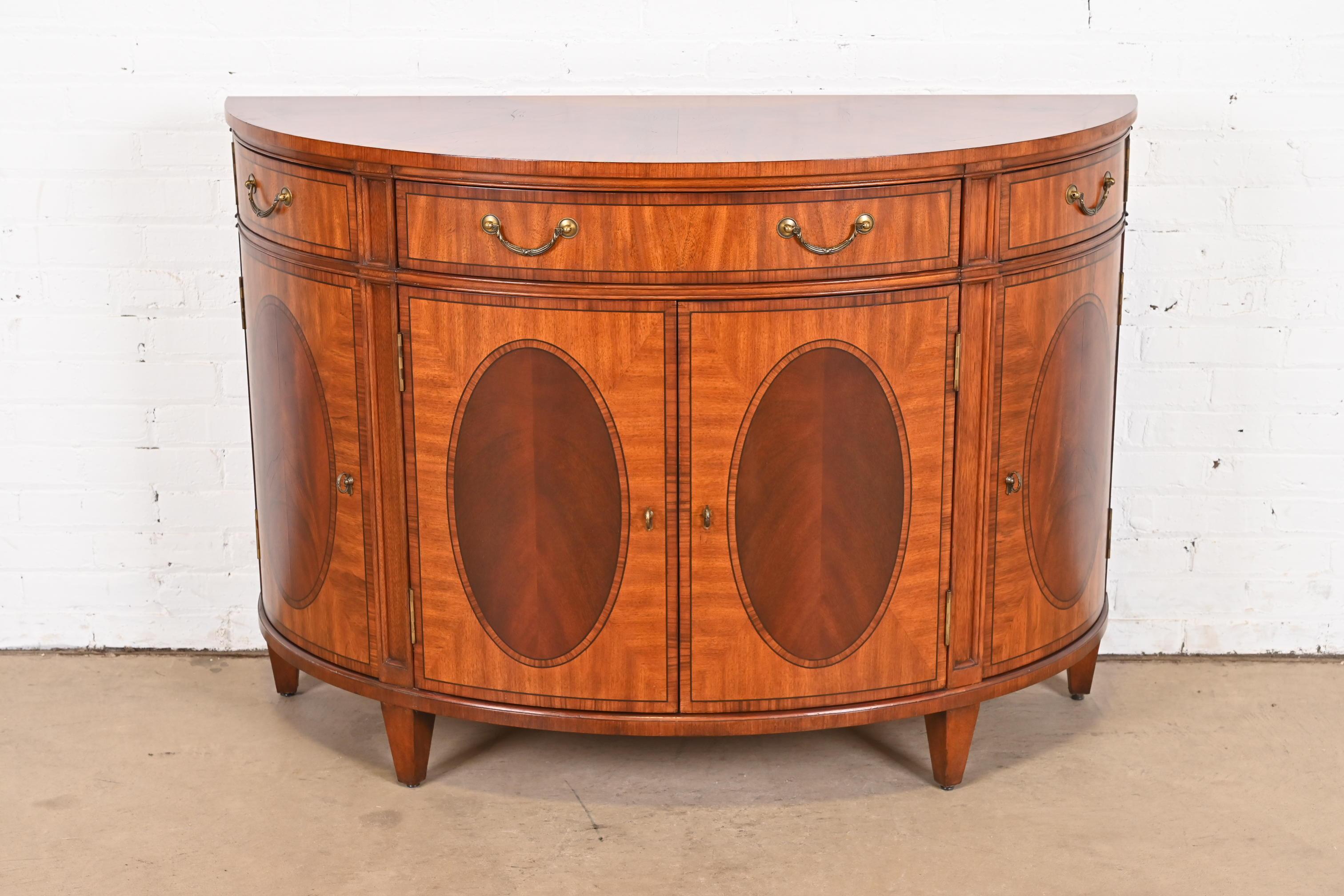 A gorgeous Regency or Georgian style demilune sideboard, console, or bar cabinet

Circa Late 20th Century

Inlaid mahogany and satinwood, with original brass hardware.

Measures: 50