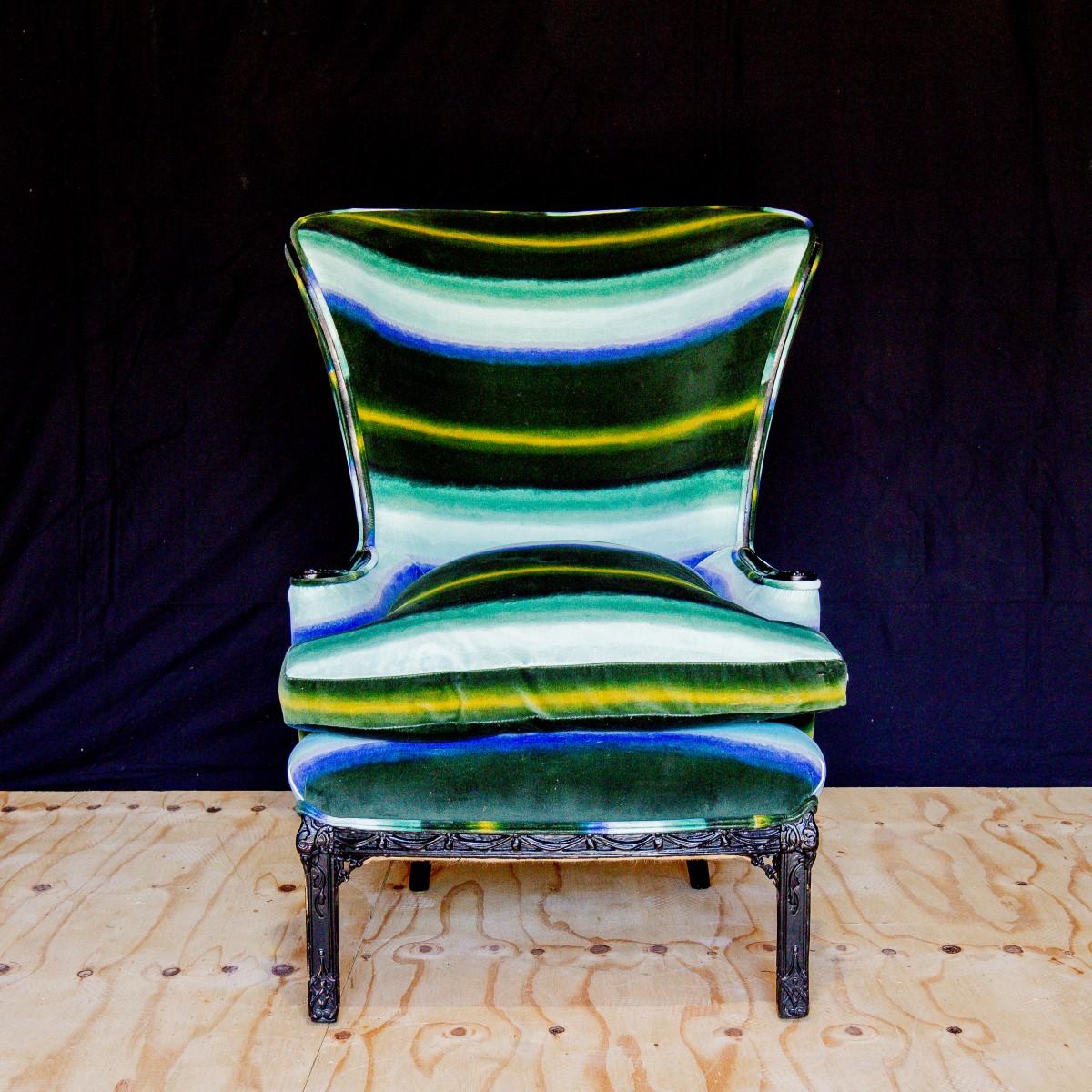 A regency inspired wingback chair with ebonised scrolling arms and carved leg detail and upholstered in a vibrant striped cotton velvet. 1950s.

