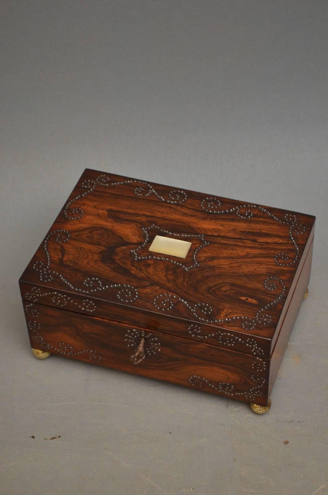 K0309, stylish Regency sewing box in rosewood with scroll decoration and hinged lid fitted with original working lock and key, enclosing relined interior, and standing on original brass feet, all in excellent home ready condition, circa