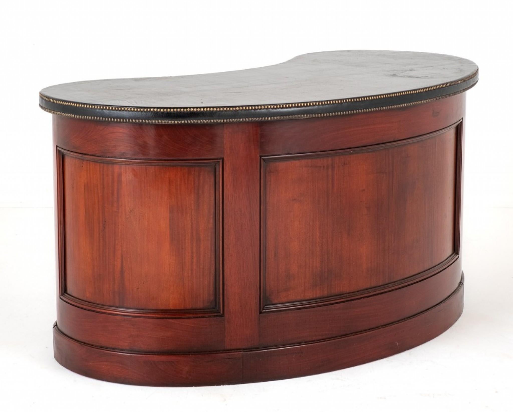 Regency Revival mahogany kidney shaped desk.
This desk stands upon a plinth base.
circa 1930
Having an arrangement of 11 working drawers which feature lions head ring pull brass handles.
The revers and sides of the desk being of a panelled