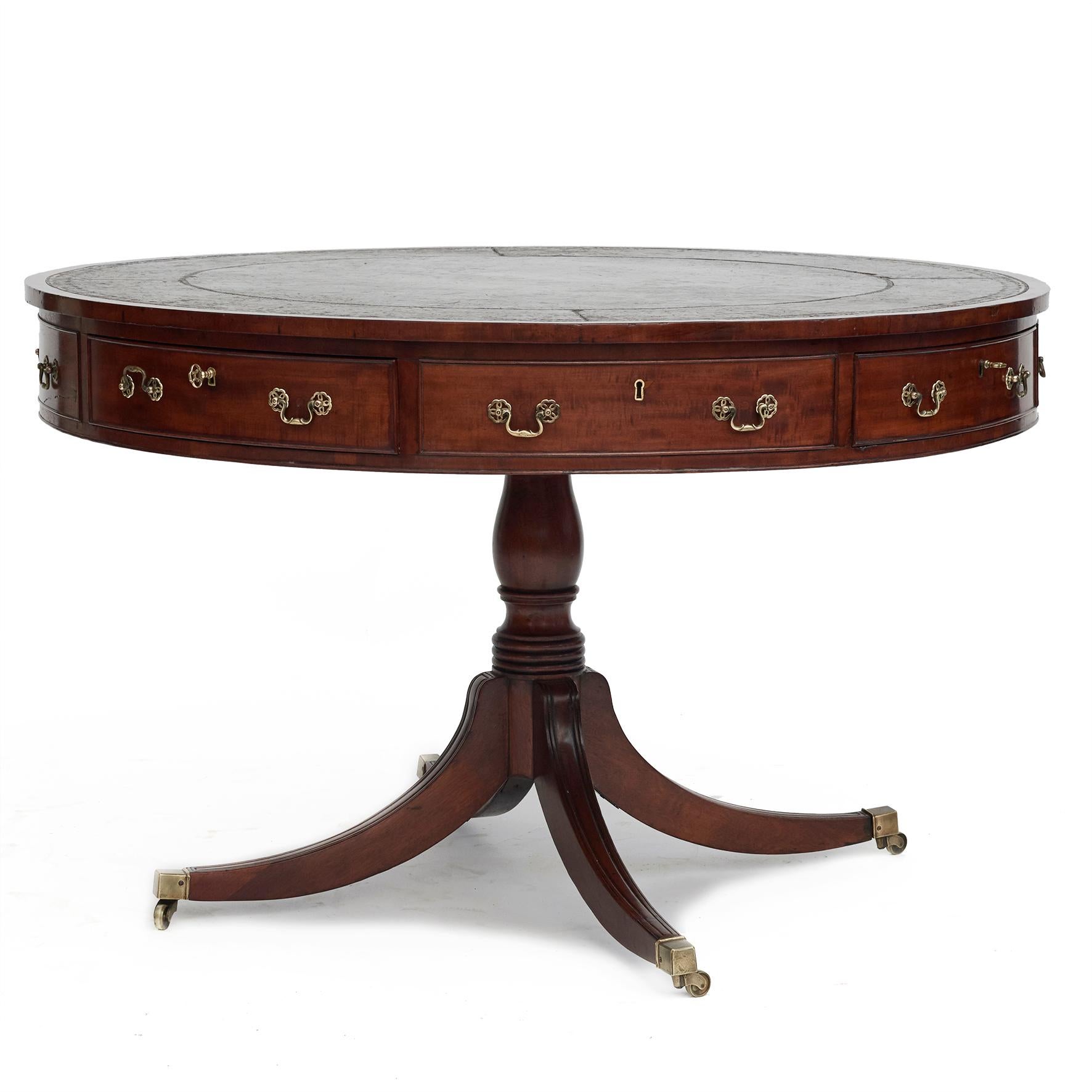 Regency period library drum table.
Mahogany frame with a circular embossed leather top with beautiful patina.
The table presents eight drawers on the apron, alternating false and working drawers with original brass fittings.
Raised on a turned