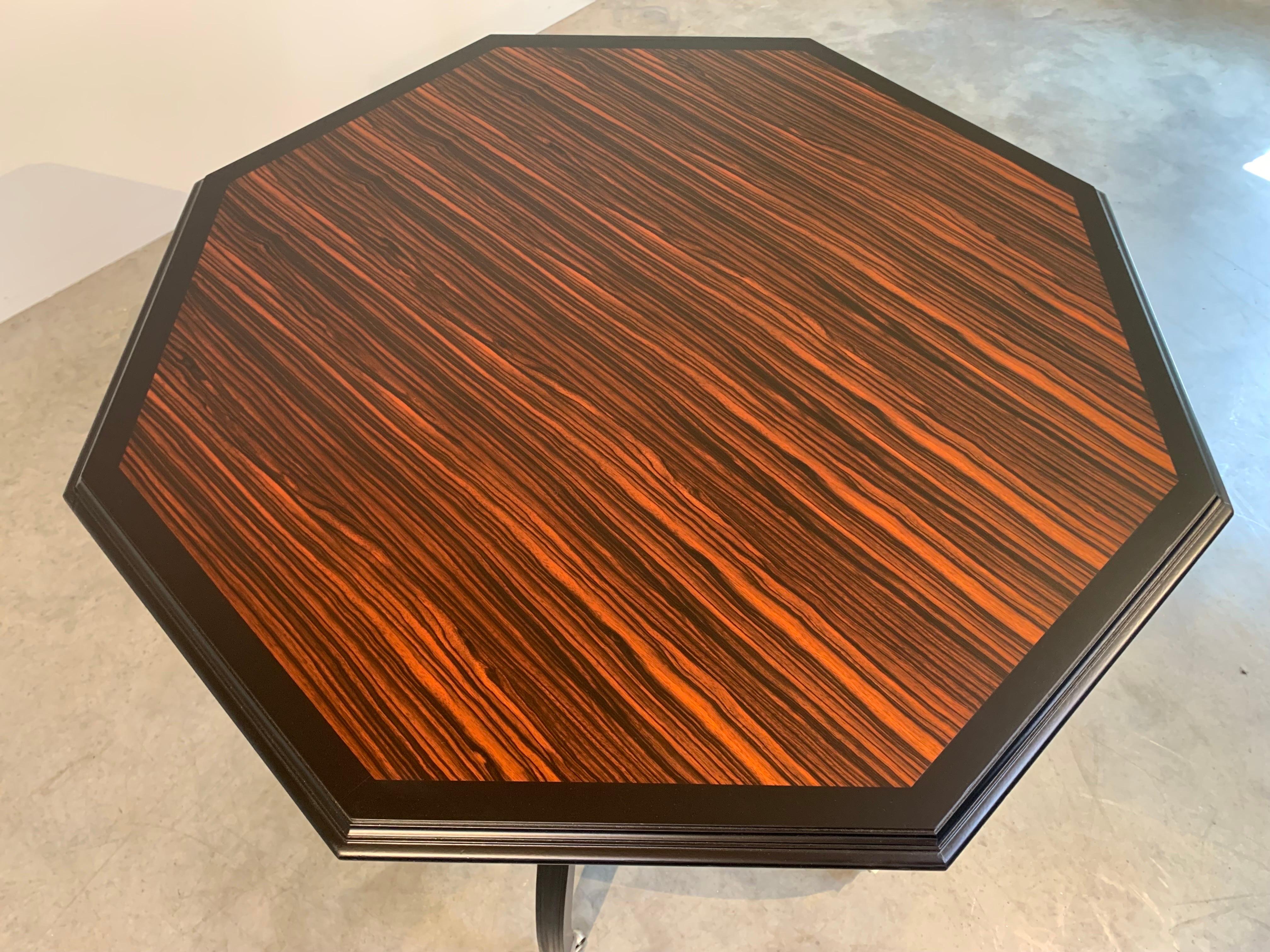 A beautiful multi-use octagonal table having Macassar ebony top with hand carved spiral center and curved legs over brushed nickel casters manufactured by Hickory Chair Company. 
In outstanding condition. Measures: 31x39x39” HWD.