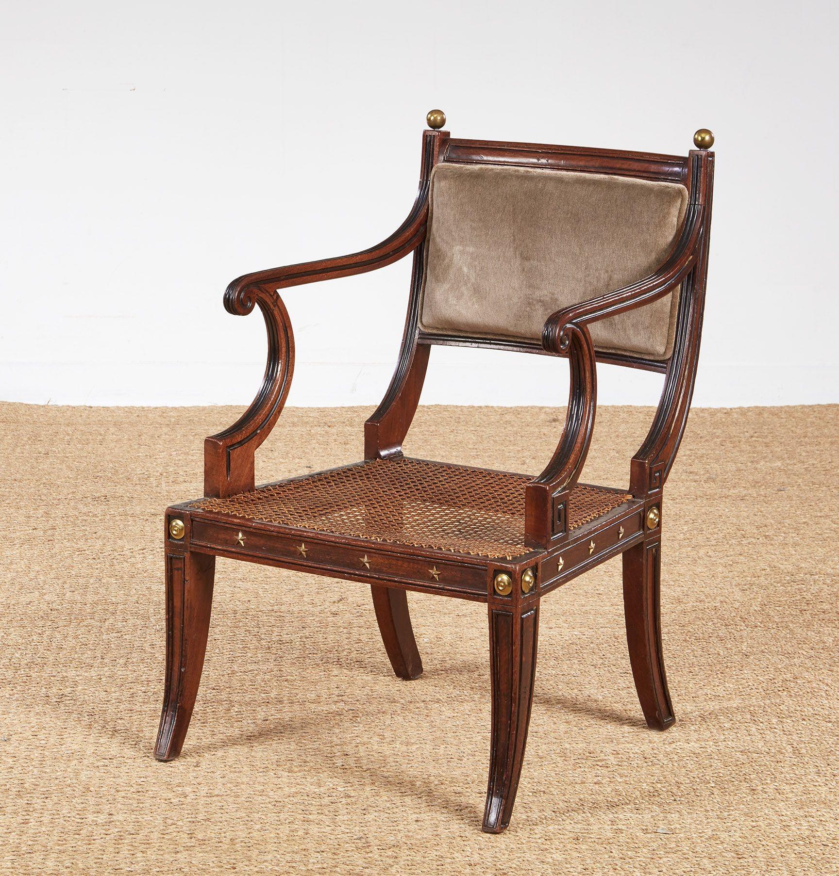 Una sedia Regency Klismos alla maniera di Thomas Hope con struttura a coste in mogano con dettagli ebanizzati, schienale sagomato e imbottito e seduta a canne, oltre a terminali decorativi a sfera in ottone sulla parte superiore, stelle in ottone