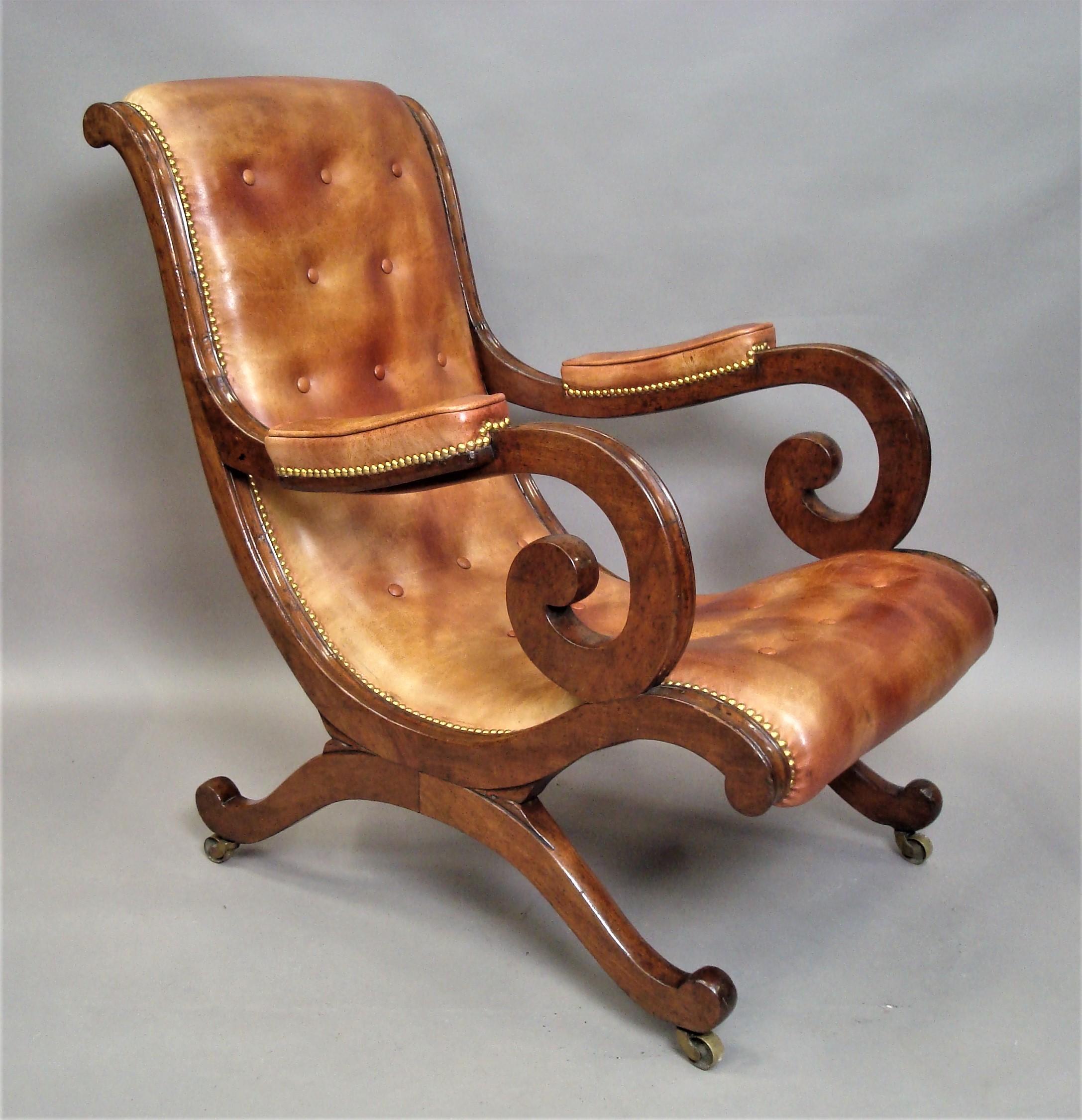 Good Regency mahogany and leather library chair; of shapely 'X' frame design; the scrolled mahogany frame with a moulded top edge and exaggerated 'C' scroll arms having padded armrest with a piped edge. The 'S' scroll continuous back and seat raised