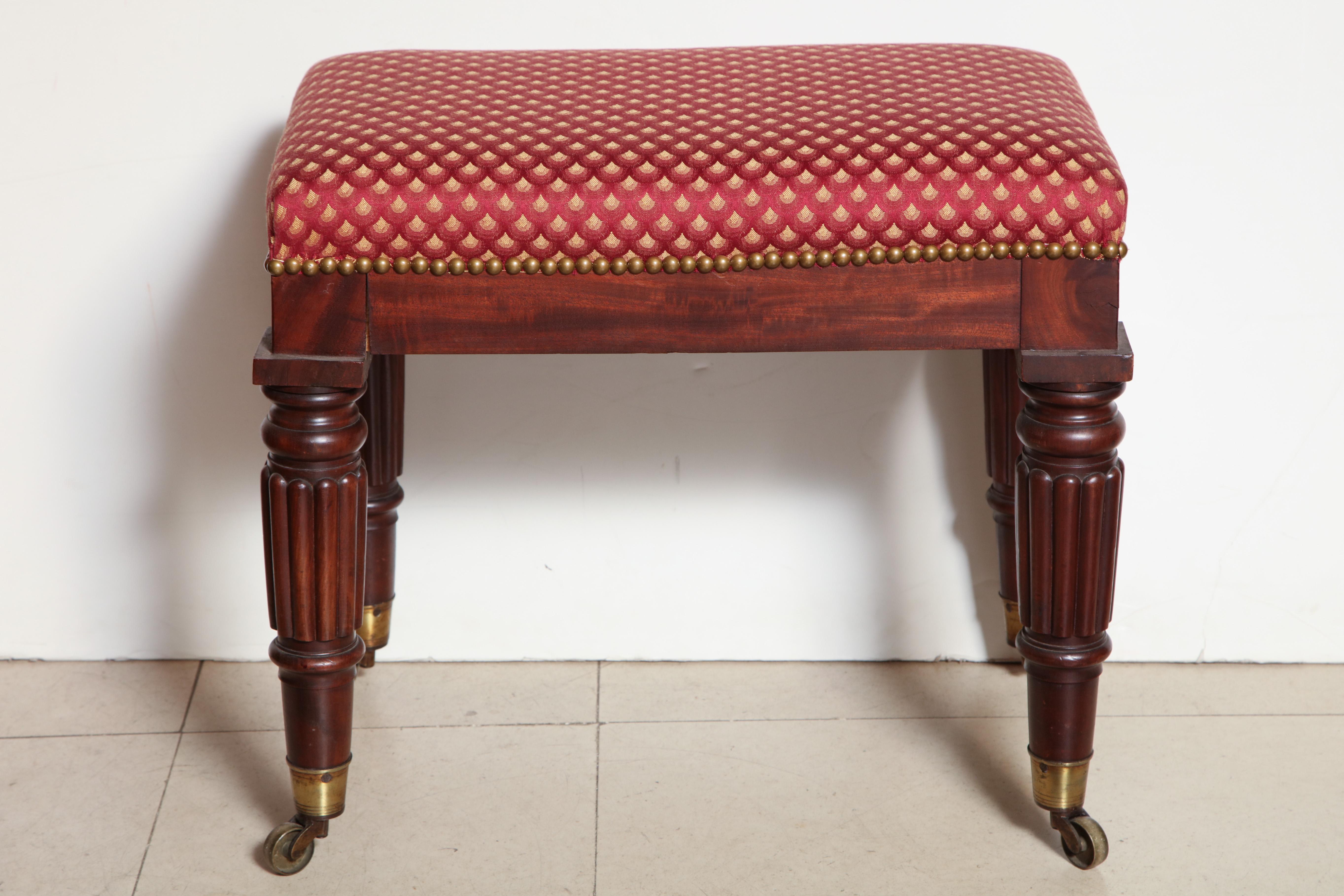 An English late Regency mahogany rectangular bench with reeded legs and raised on brass casters.