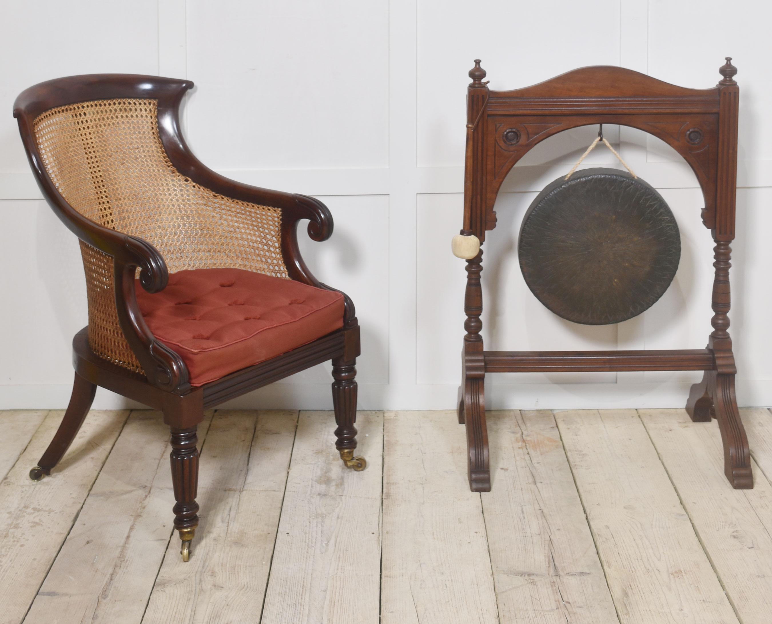 Poltrona bergere del periodo Regency, poltrona da biblioteca con struttura in mogano massiccio, con ringhiera sagomata e braccioli a voluta, schienale bergere, fianchi e seduta con cuscino sfoderabile. Si erge su gambe anteriori con nervature e
