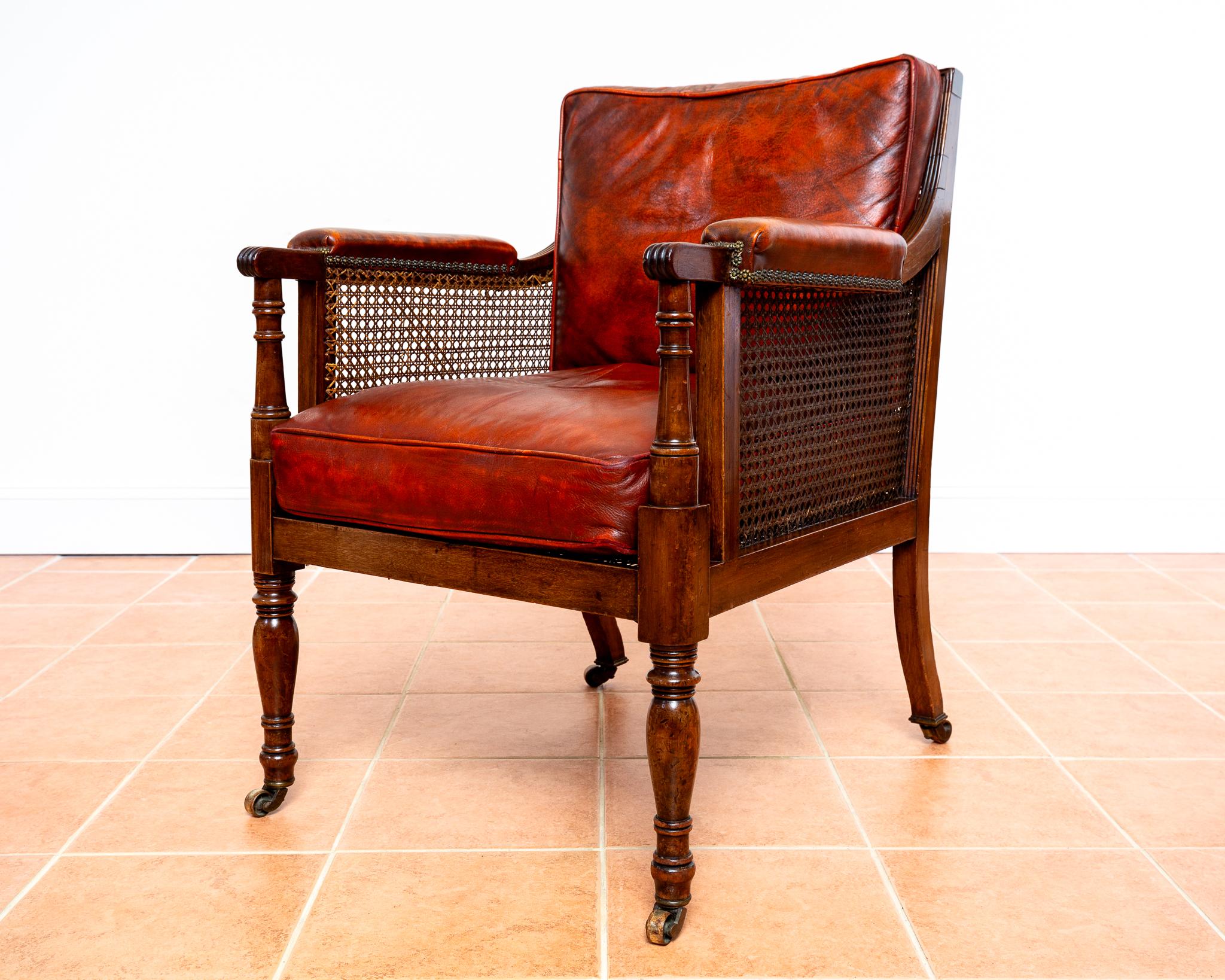 A gorgeous, fine and extremely rare mahogany and leather Regency bergere library armchair in fabulous antique condition. Most likely crafted around 1810-20 during England’s Regency period, this extremely impressive armchair exudes stately charm,