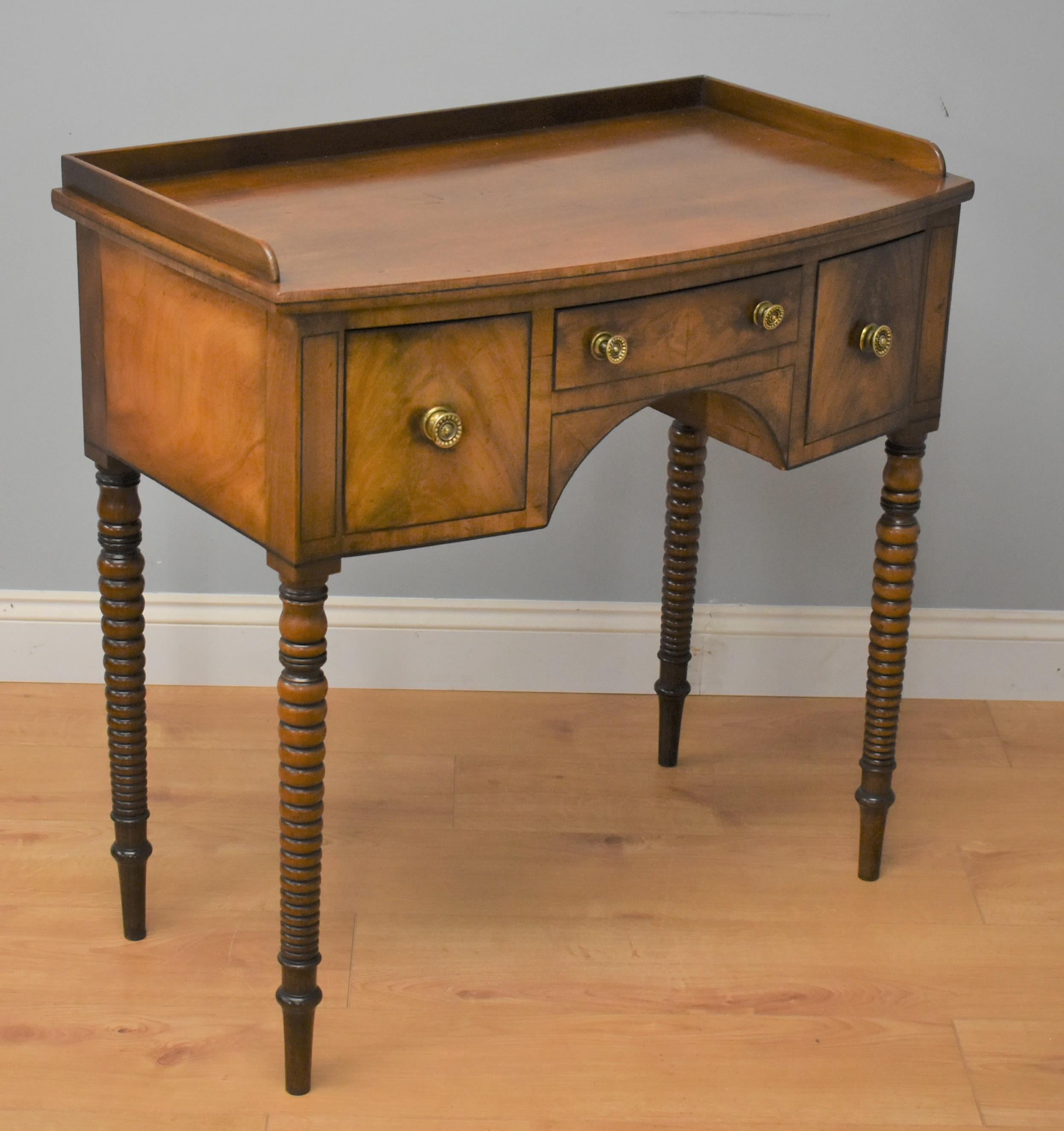 Regency mahogany bow front side table in very nice condition having been polished by traditional methods. The side table has three drawers one long to the centre and on either side a deep drawer. The side table stands on turned legs.