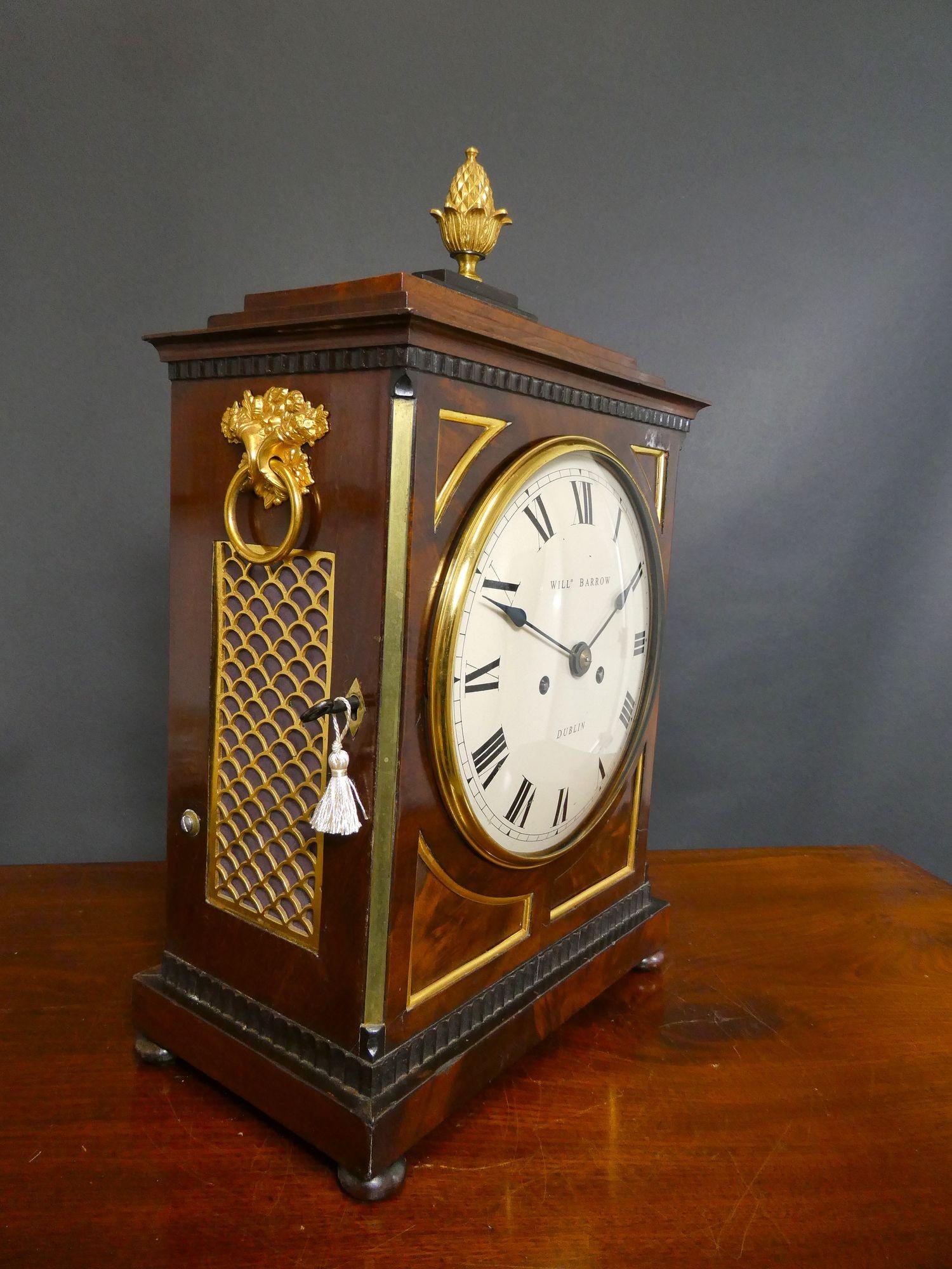 Regency Mahogany Bracket Clock, William Barrow, Dublin

Regency bracket clock housed in a finely figured mahogany brass bound case with chamfer top. Side carrying handles, silk lined sound frets and glazed rear door, standing on ball feet and