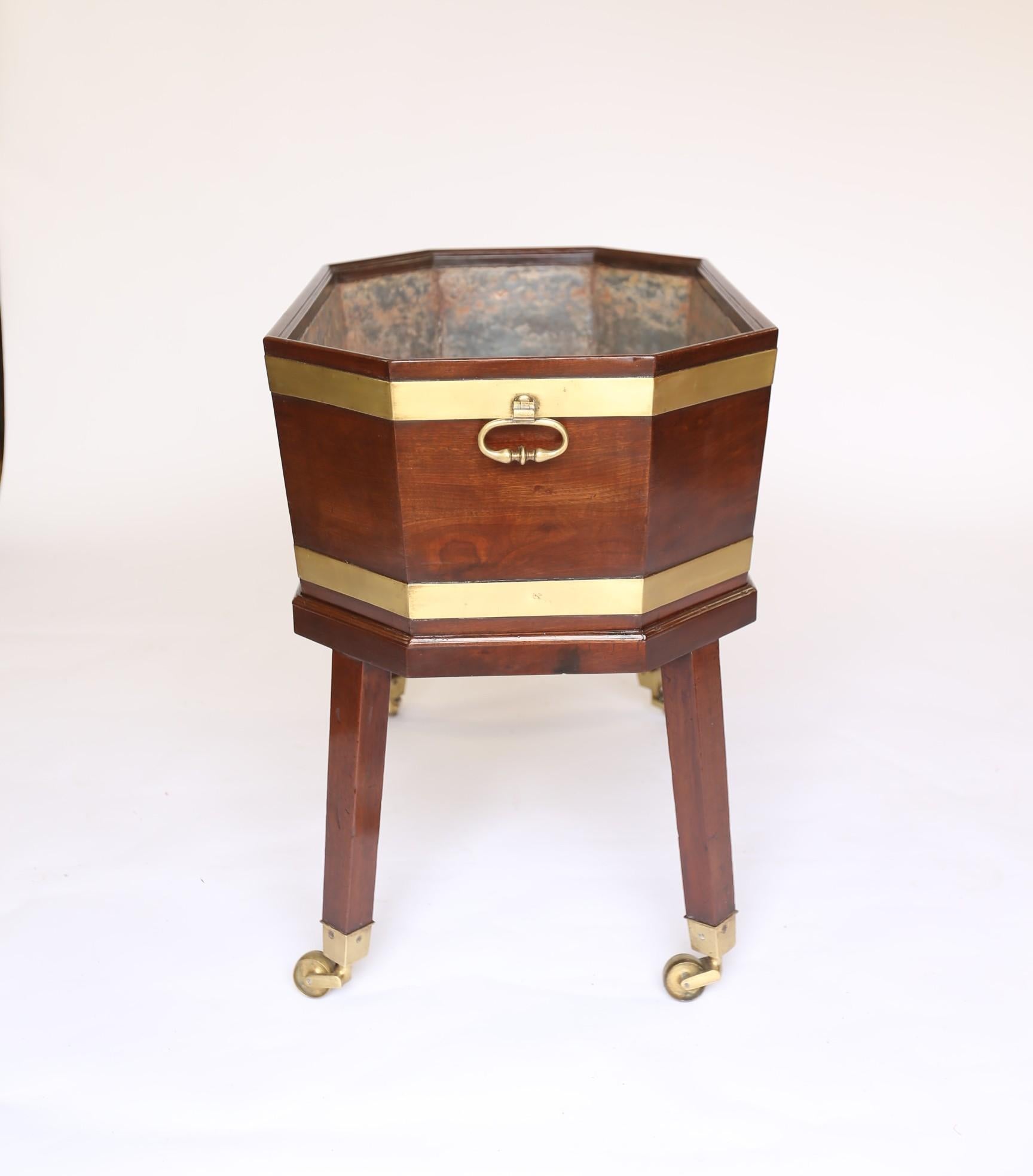 Regency Mahogany & Brass bound Wine Cooler/  Cellaret on stand
Zinc Lined. 
Brass bound in very good original condition
Pair Cast Brass Carry Handles, Each Side.
Sitting On original Base with Tapering Square legs &
Brass Castors,
Recently Polished