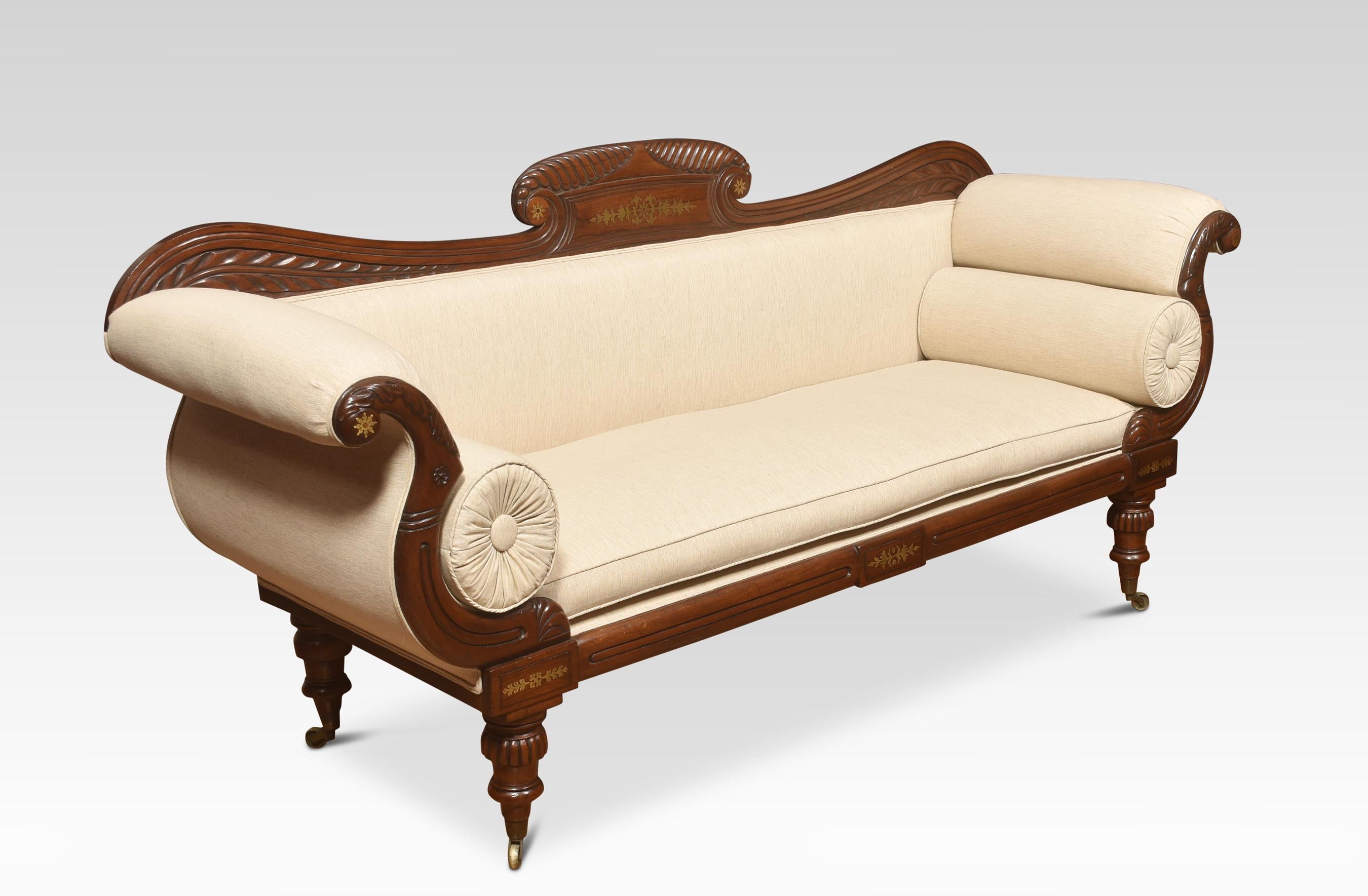 Early 19th-century mahogany framed scroll end settee, the acanthus scrolling arched top rail with brass detail above back and seat flanked by scrolling upholstered arms. Standing on foliated tapered legs with brass caps and