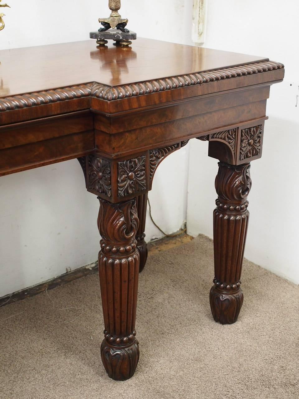 Regency inverted breakfront hall or serving table in Spanish flame mahogany, circa 1820. The inverted breakfront top is in mirror matched Spanish mahogany with a gadrooned edge above a deep moulded frieze. It has a centre drawer to the frieze, and