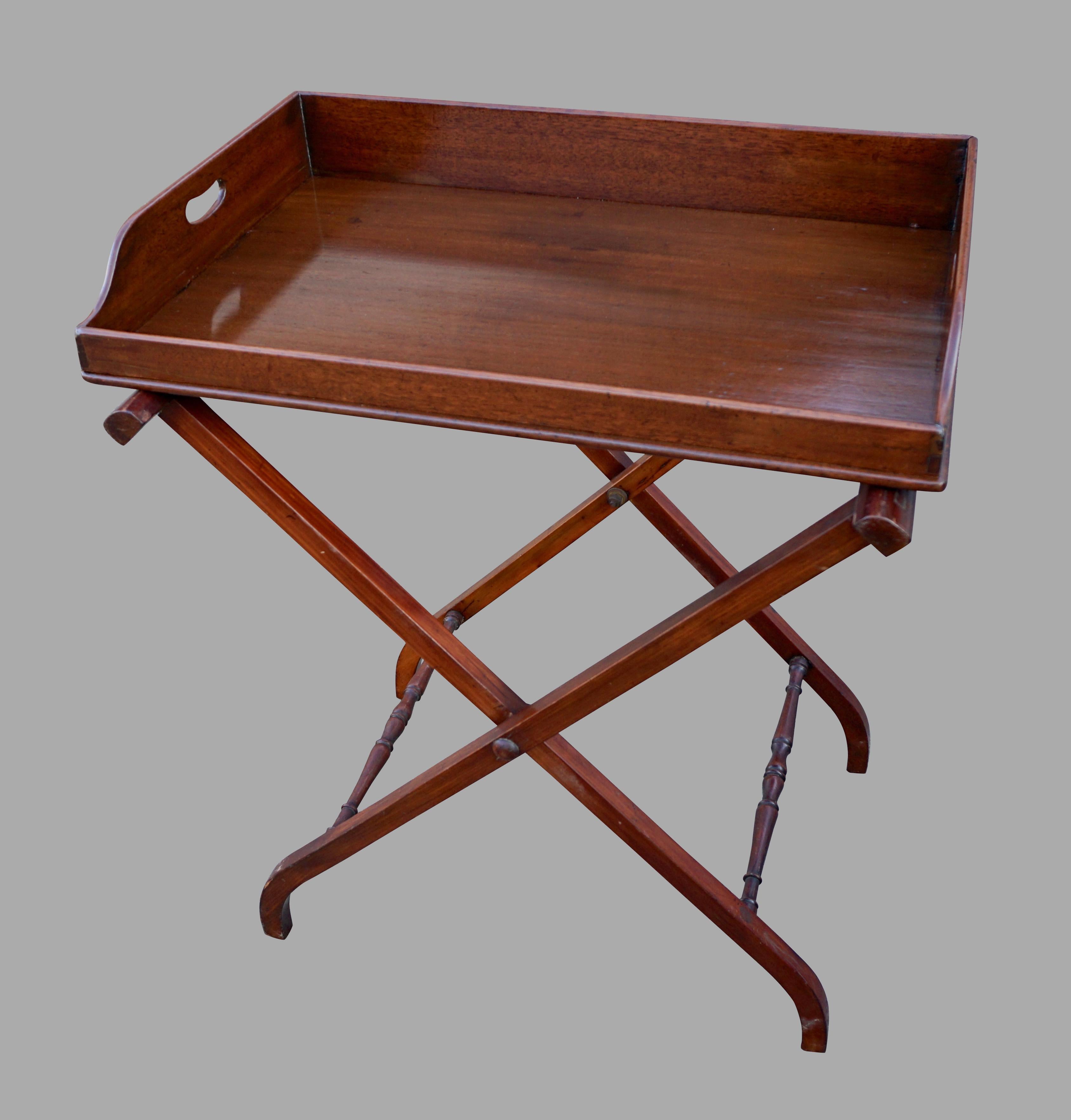 An English Regency period mahogany butler's tray of typical form with side cutout handles.
The front is lower than the sides for easy access. Now resting on an antique mahogany stand of a later date. Tray is early 19th century.