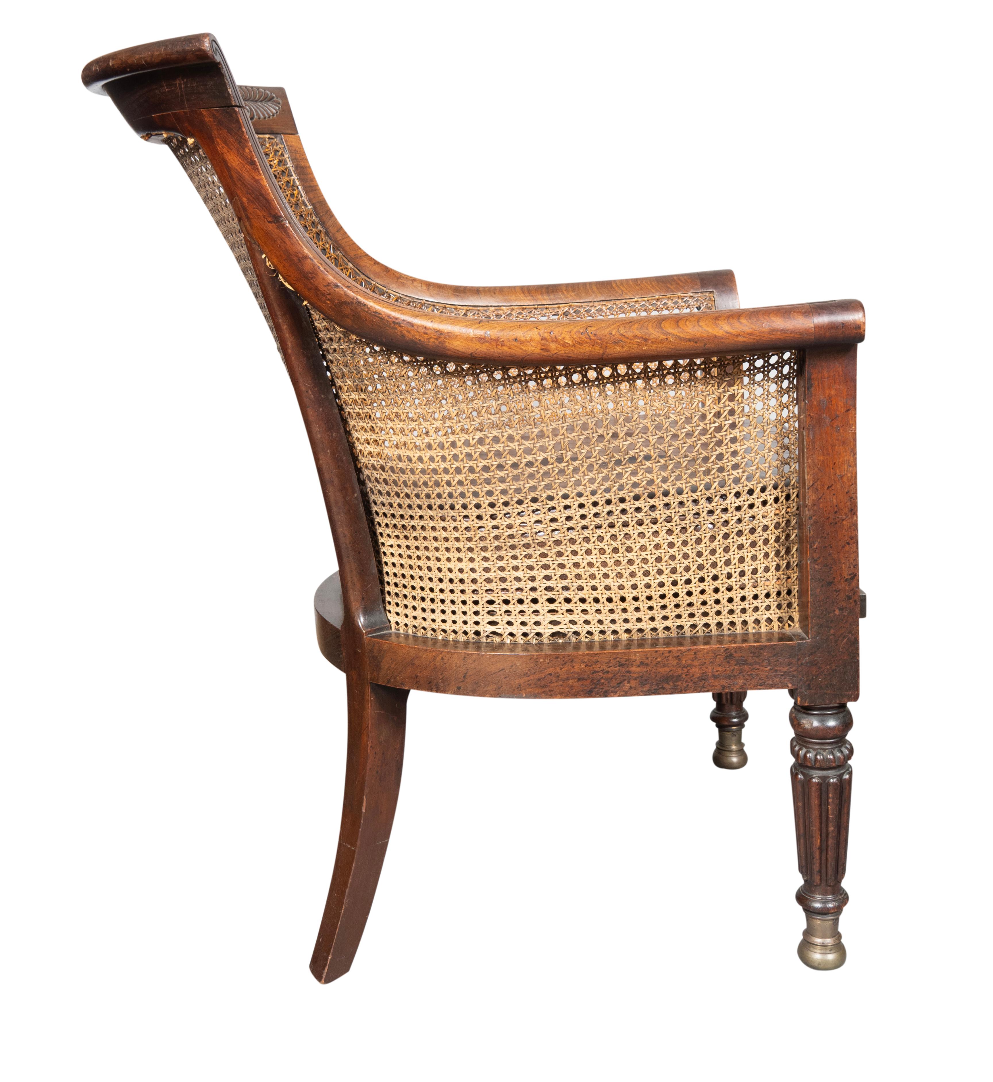 With curved caned back and crestrail with anthemion carving, caned seat additional caned panel to protect seat with brown leather cushion. Scrolled arm terminals. With circular tapered reeded legs ending on brass caps. Very comfortable with great