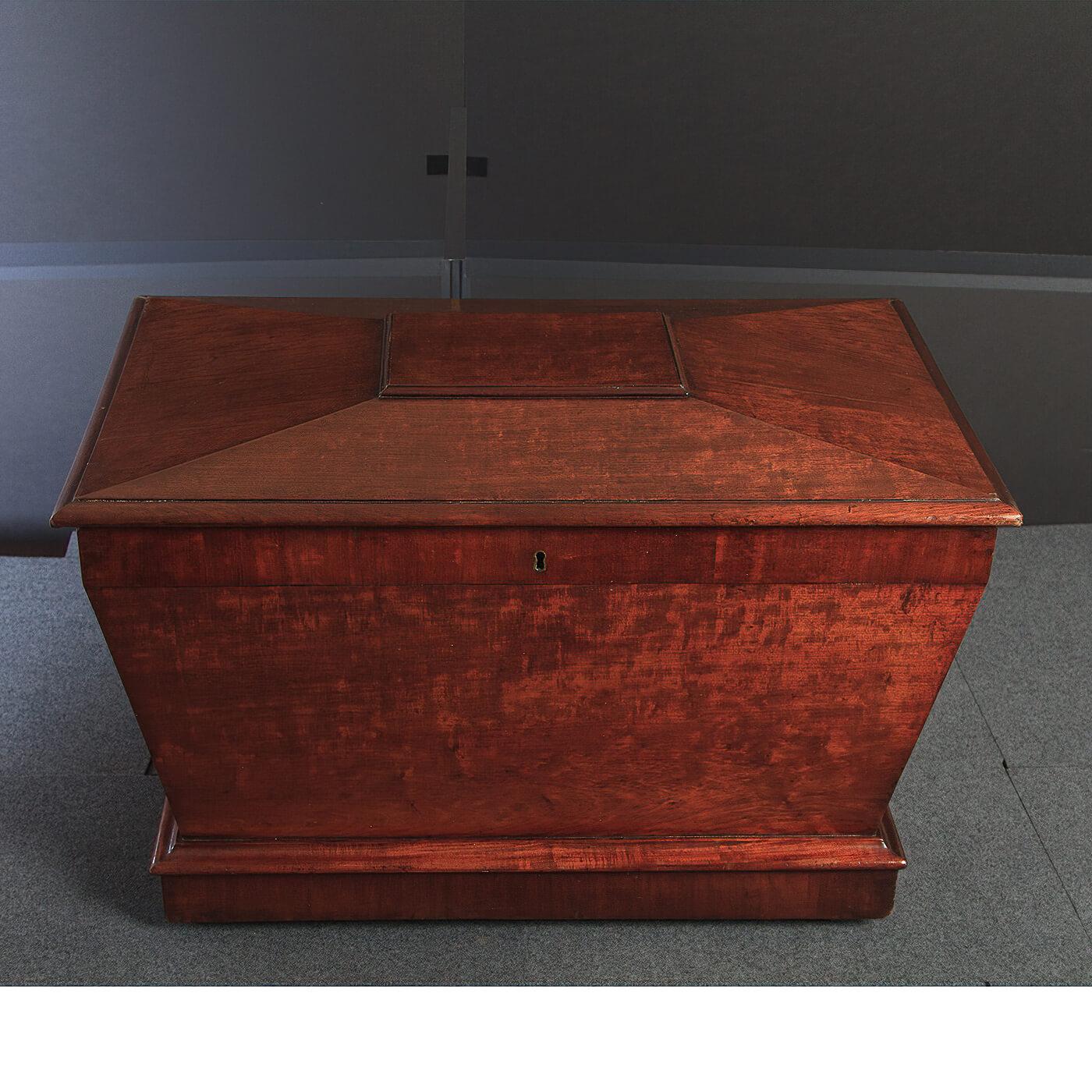 A fine English Regency mahogany sarcophagus form cellarette. With a lift top, lion head bronze mounts with ring handles and raised on casters. England, circa 1810.

Dimensions: 29