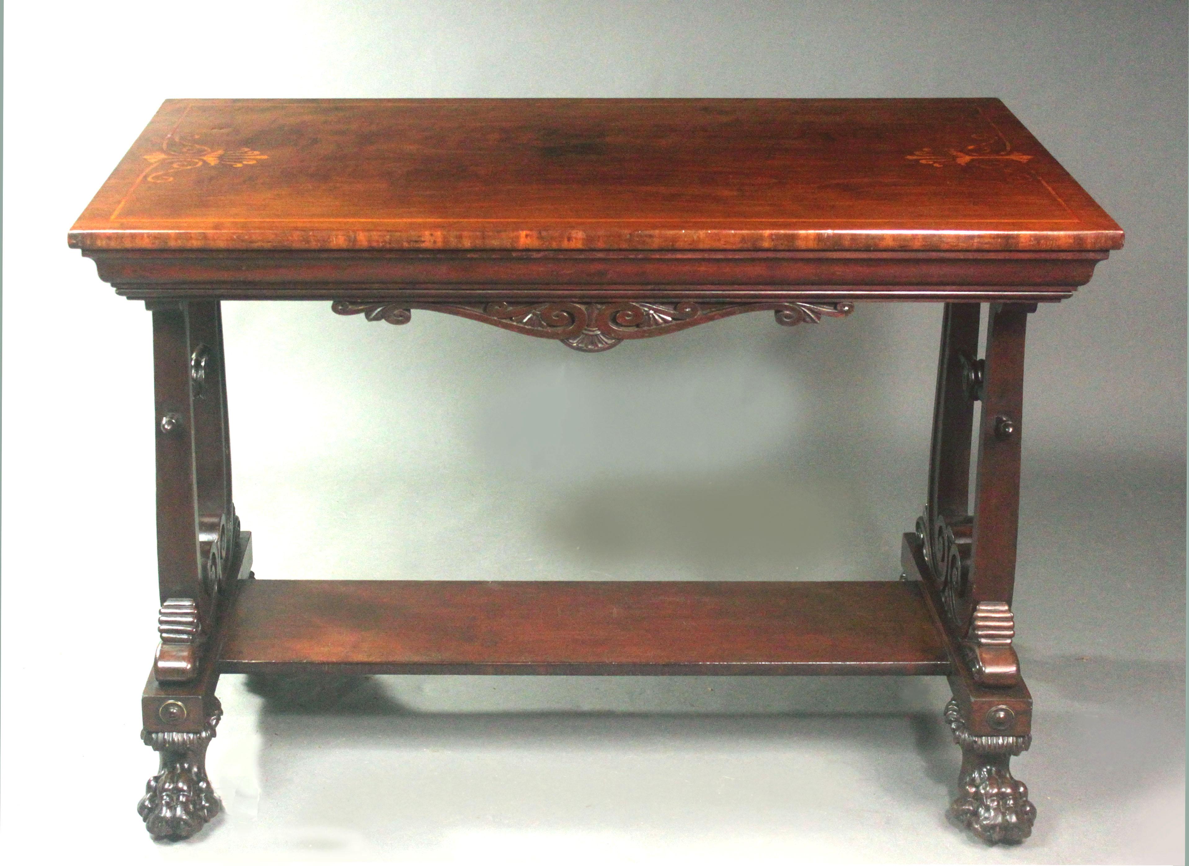 A Regency mahogany centre table in the manner of George Smith with fine detail: the top with inlaid anthemions in satinwood, the frieze with carving and ogee moulding, the standard ends formed with large S-scrolls, platform base and handsome carved