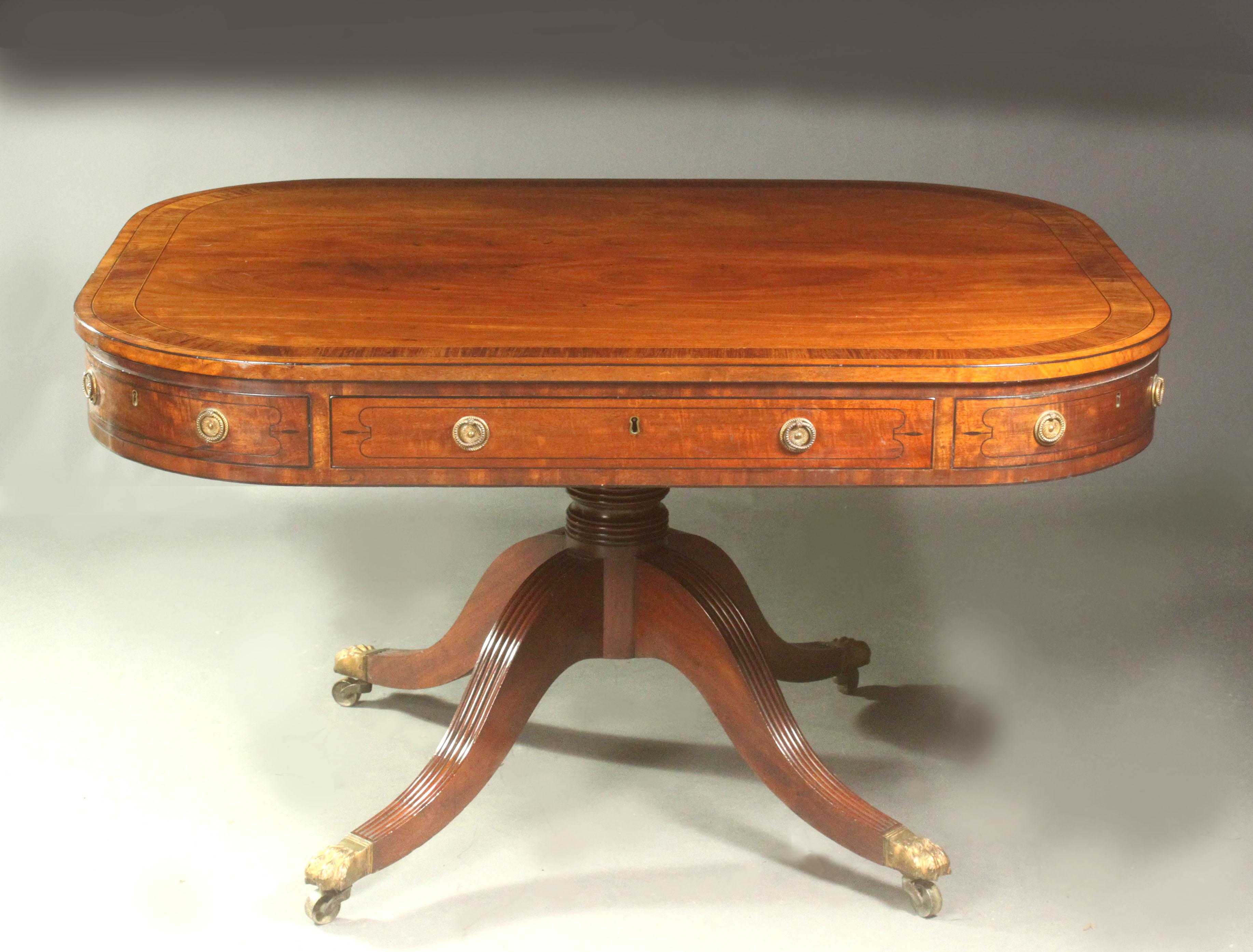 A fine Regency mahogany centre table in the manner of Gillows of Lancaster; the four-splay reeded sabre leg base with turned pillar; the figured mahogany top with kingwood cross-banding and boxwood and ebony stringing; the carcase fronts with