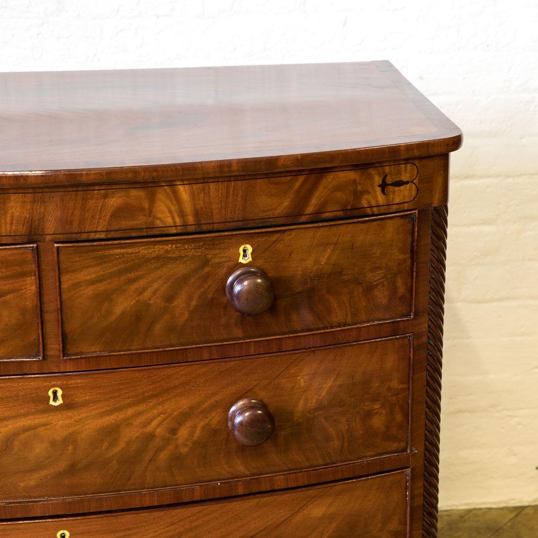 A very attractive Regency bow fronted chest of drawers, circa 1810. With elegant splayed feet below three under drawers, all with their original turned knobs. The rope twist corners are typical of the period as is the ebony inlay to the frieze and