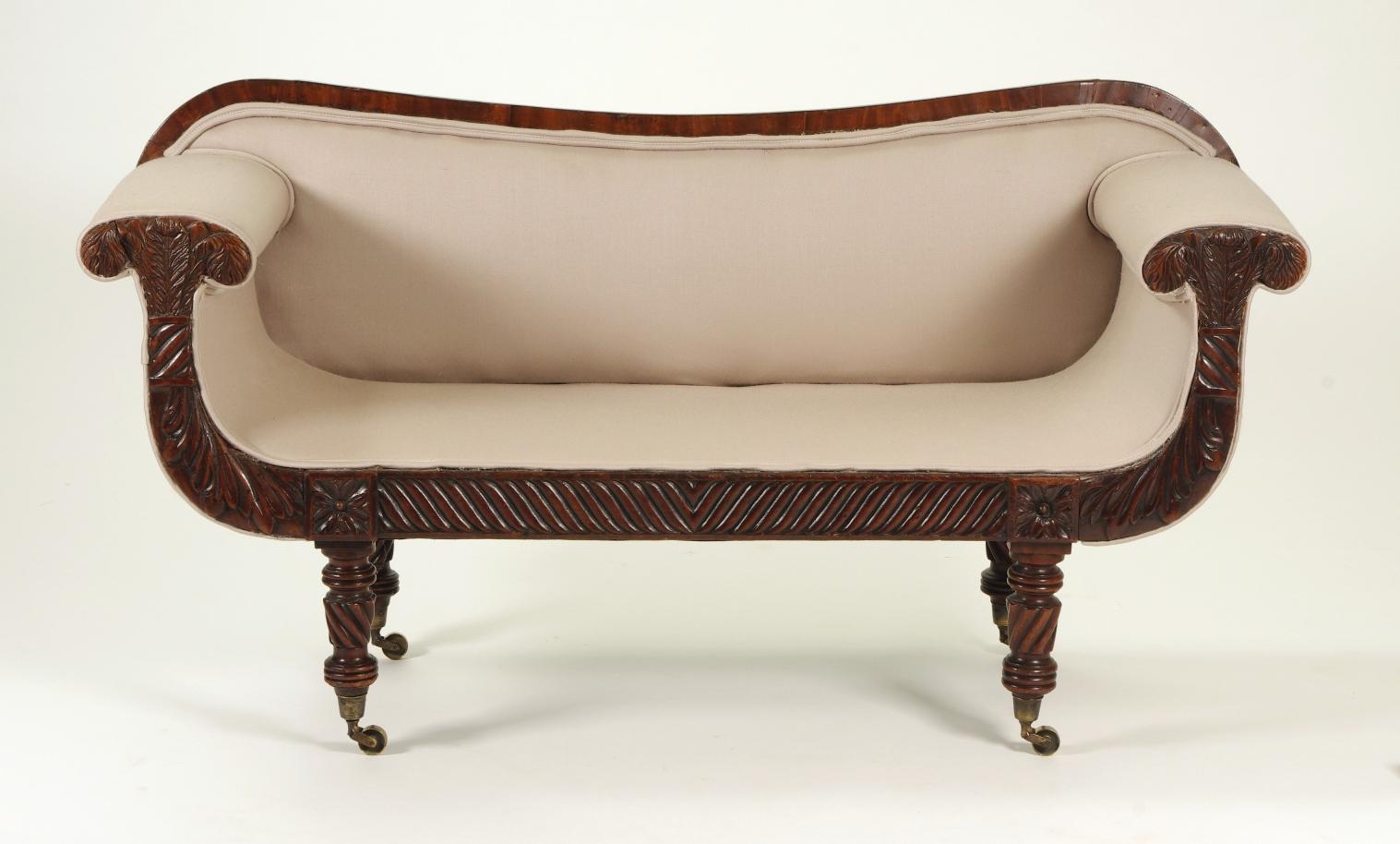 Regency mahogany child's sofa, the serpentine top rail over the upholstered seat and back; the mushroom arms with Prince of Wales feathers and acanthus leaves raised on turned legs headed by carved rosettes and ending with brass casters, joined by a