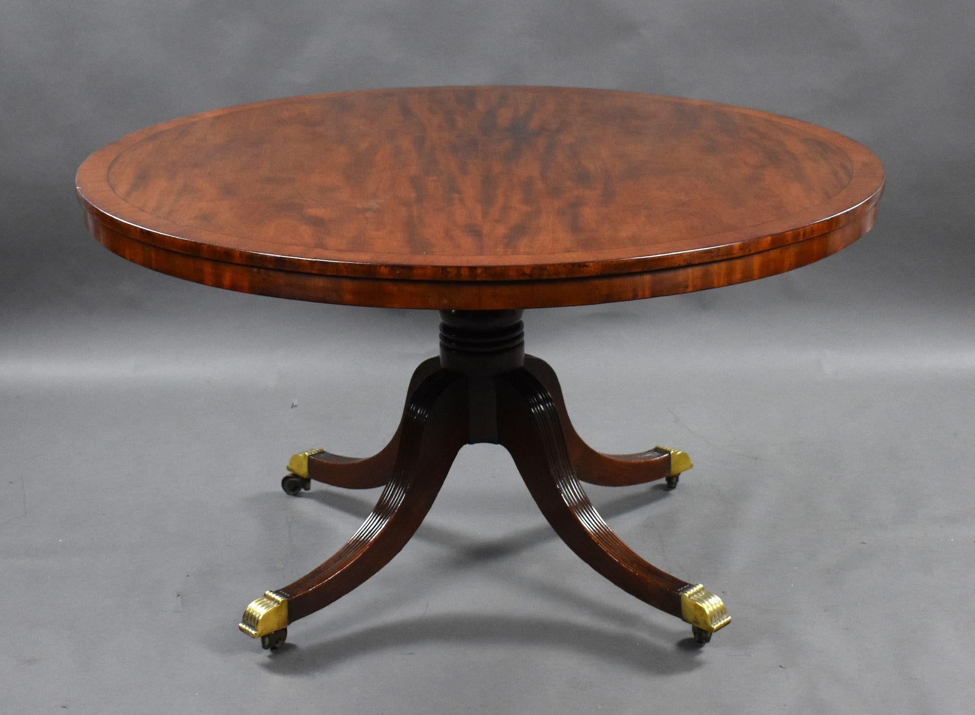 For sale is a good quality, possibly Irish, Regency mahogany circular breakfast table, the fiddleback mahogany top with an ebony inlaid border on four reeded and swept legs terminating on original brass castors. This piece was purchased from Elveden