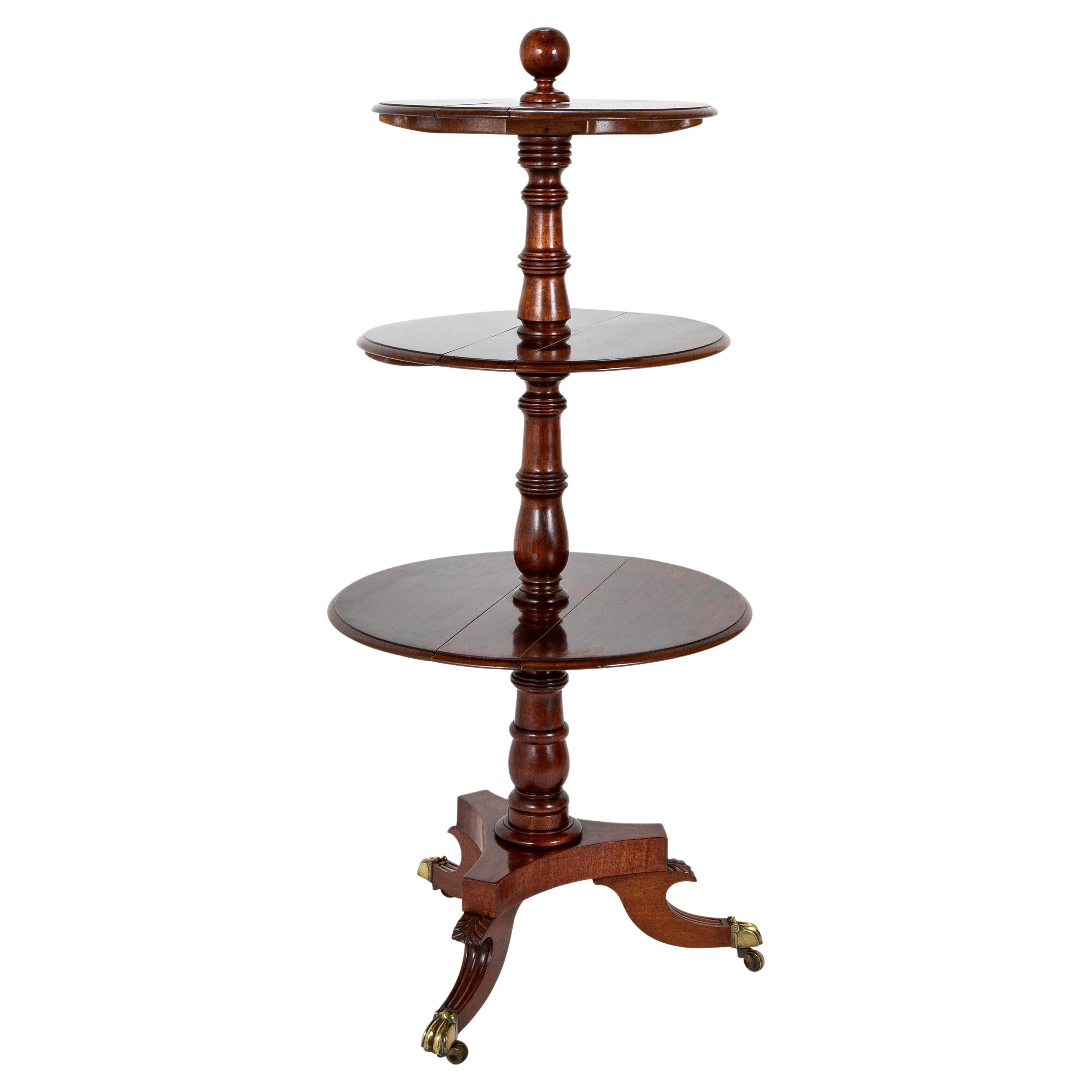 A lovely 19th century English Regency mahogany three tiered etagere or dumbwaiter with three circular shelves that fold. The central turned support resting on a tripod base of three elegant legs with acanthus leaf carving ending in the original paw