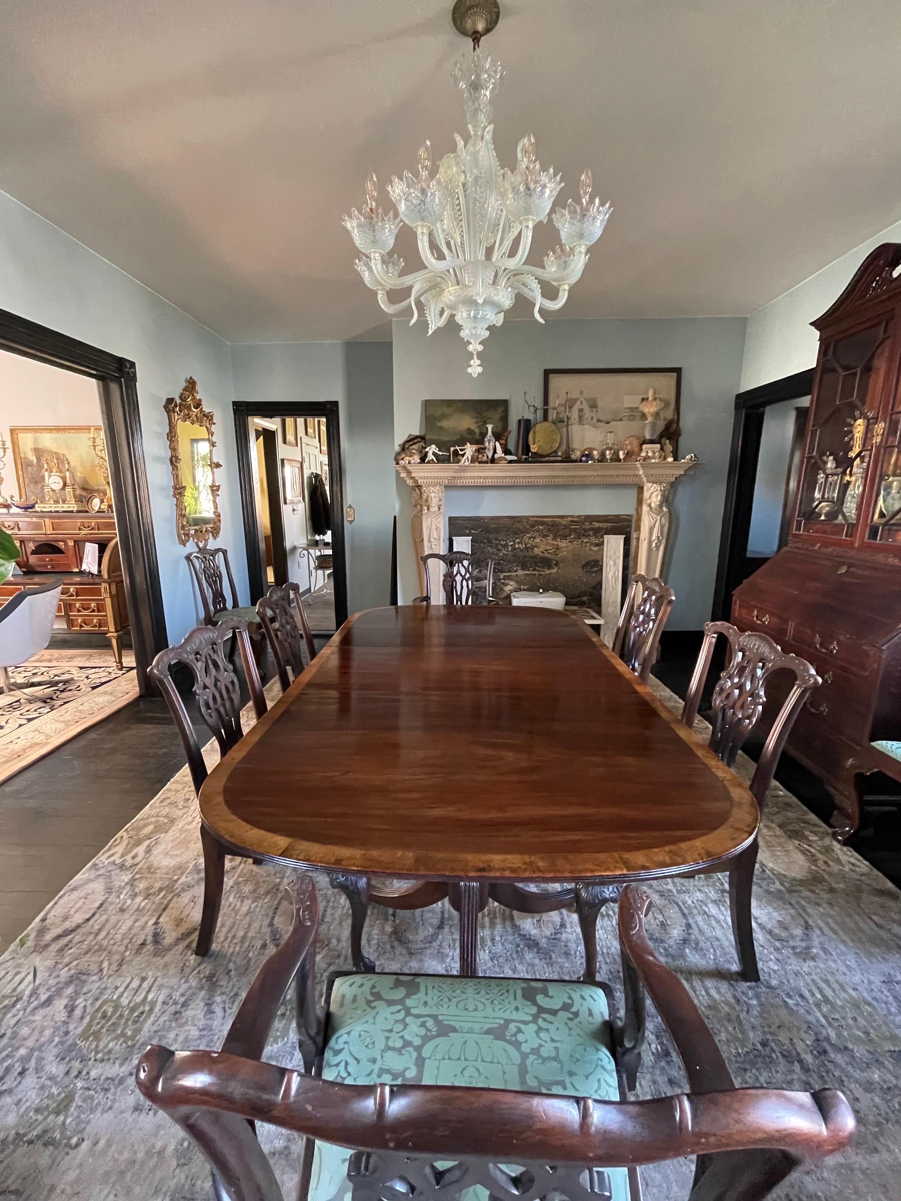 An elegant late 19th century Regency solid mahogany two pedestal dining table with two large leaves seating 8-10 people. 
The mahogany top has a vibrant pattern and retains its original contrasting border made of European Walnut. The finish has