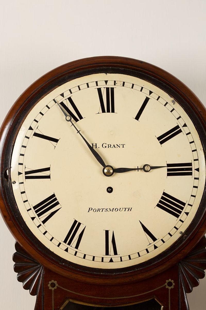Regency drop dial clock with brass inlay and cast brass bezel. 
Convex painted dial signed ‘H.Grant, Portsmouth’. With Roman numerals and original ‘blued’ steel ‘moonpoise’ hands. 
Eight day fusee movement with shouldered brass plates. C.1830
 
