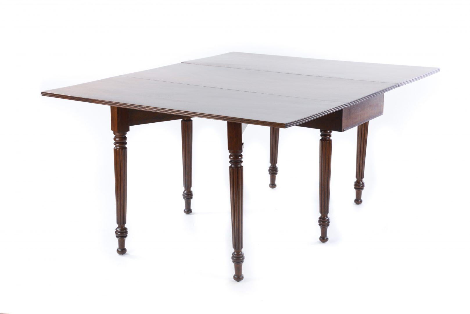 A Regency mahogany drop leaf dining table in the style of Gillows, with drop leaves, raised on fluted supports.

Gillows of Lancaster and London, also known as Gillow & Co., was an English furniture making firm based in Lancaster, Lancashire, and
