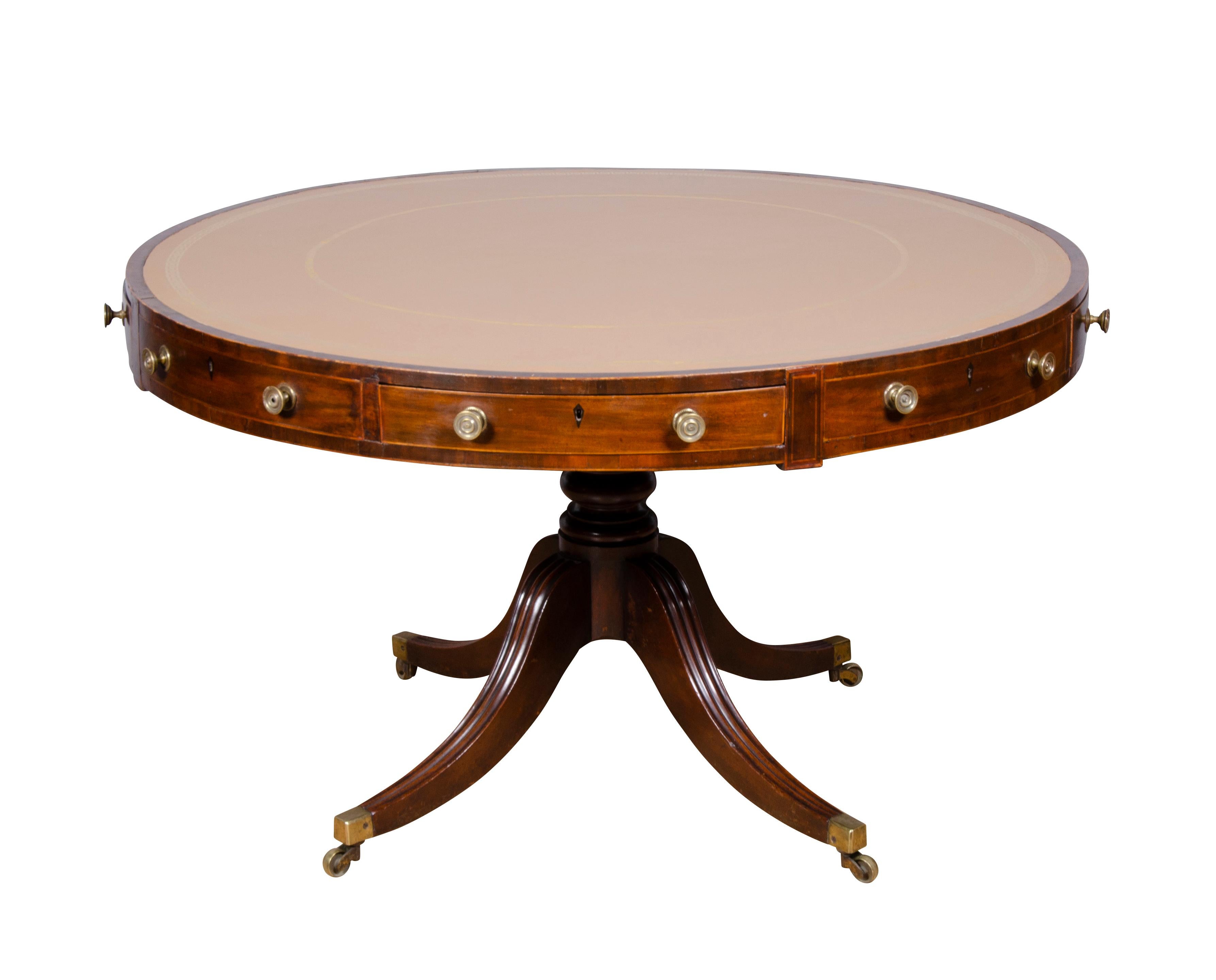 Circular top with inset tan leather over drawers, raised on four splayed legs and casters.