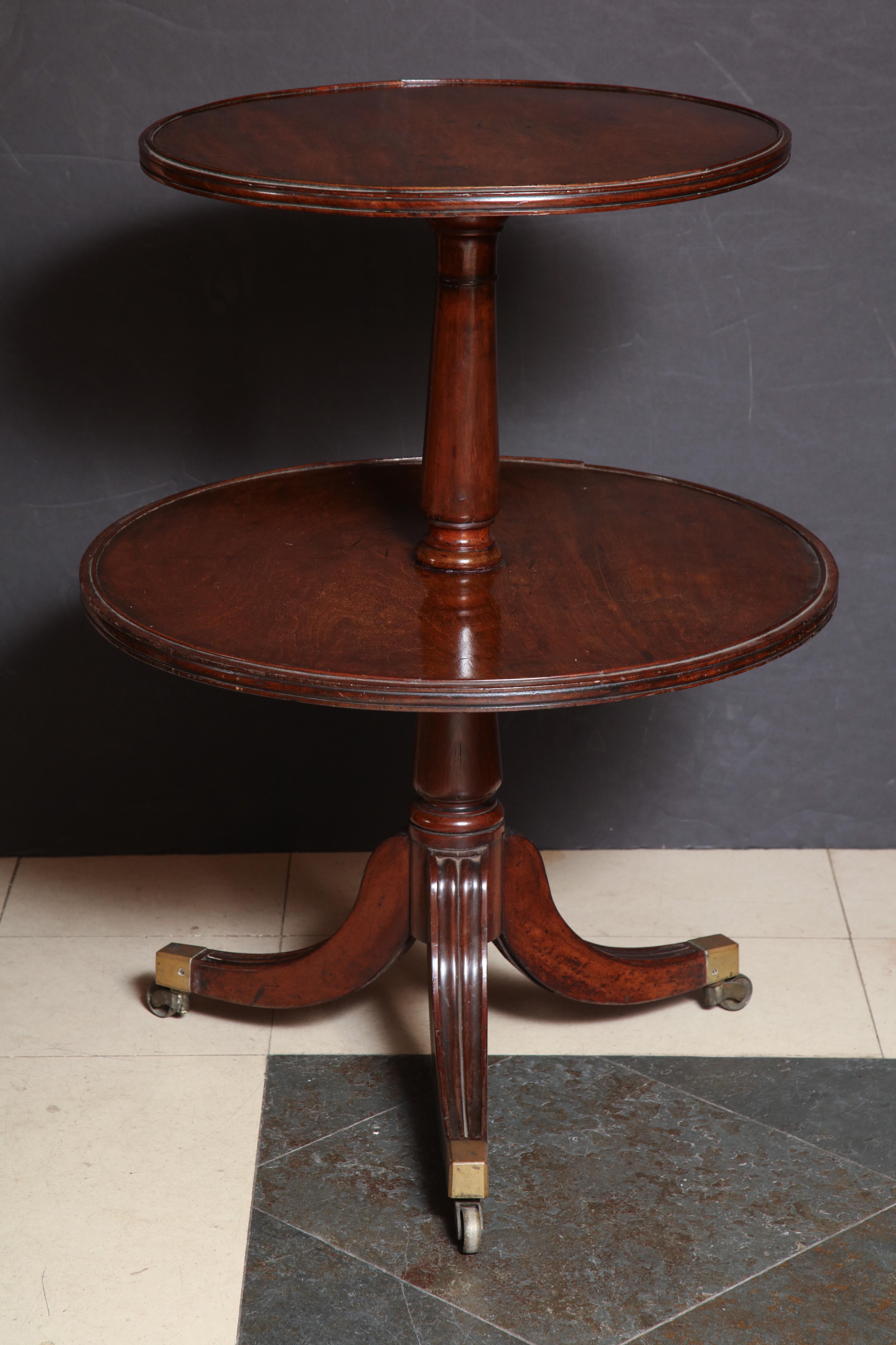 English Regency mahogany two-tier dumbwaier with a turned pedestal on sabre legs with brass casters.
 