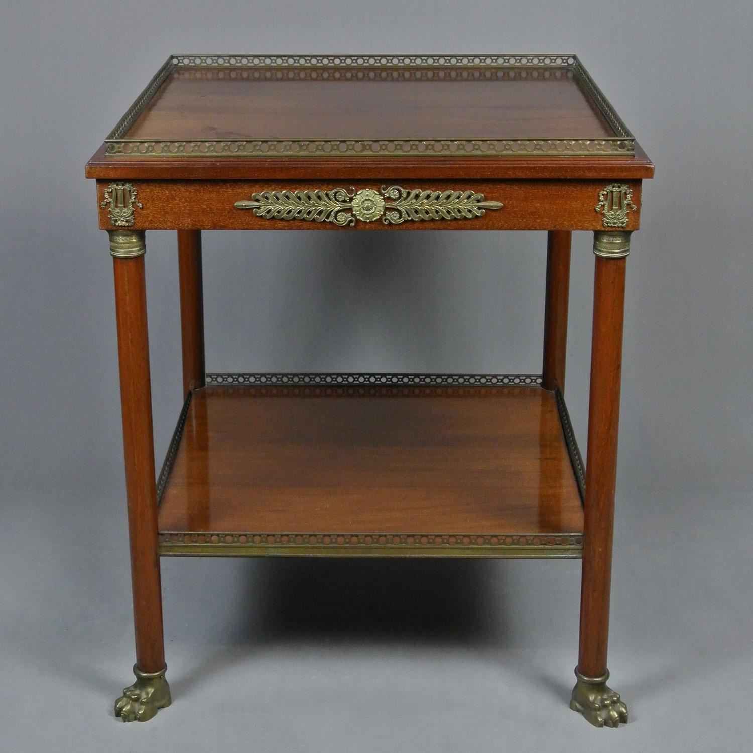 A very fine solid mahogany two tier centre table with intricate original brass galleries, ormolu mounts and lovely solid brass lion paw feet.

Both shelves formed from single boards of mahogany and bordered with a beautiful solid brass gallery of