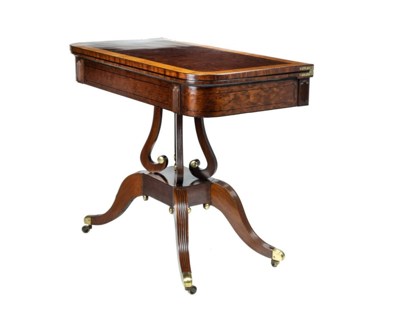 A Regency mahogany Empire style fold over tea table, circa 1815, attributed to Thomas Hope, ebony strung and brass-mounted, the four splayed legs supporting four angled lyre scroll and reeded columns, the swivel top opening to reveal plumb pudding