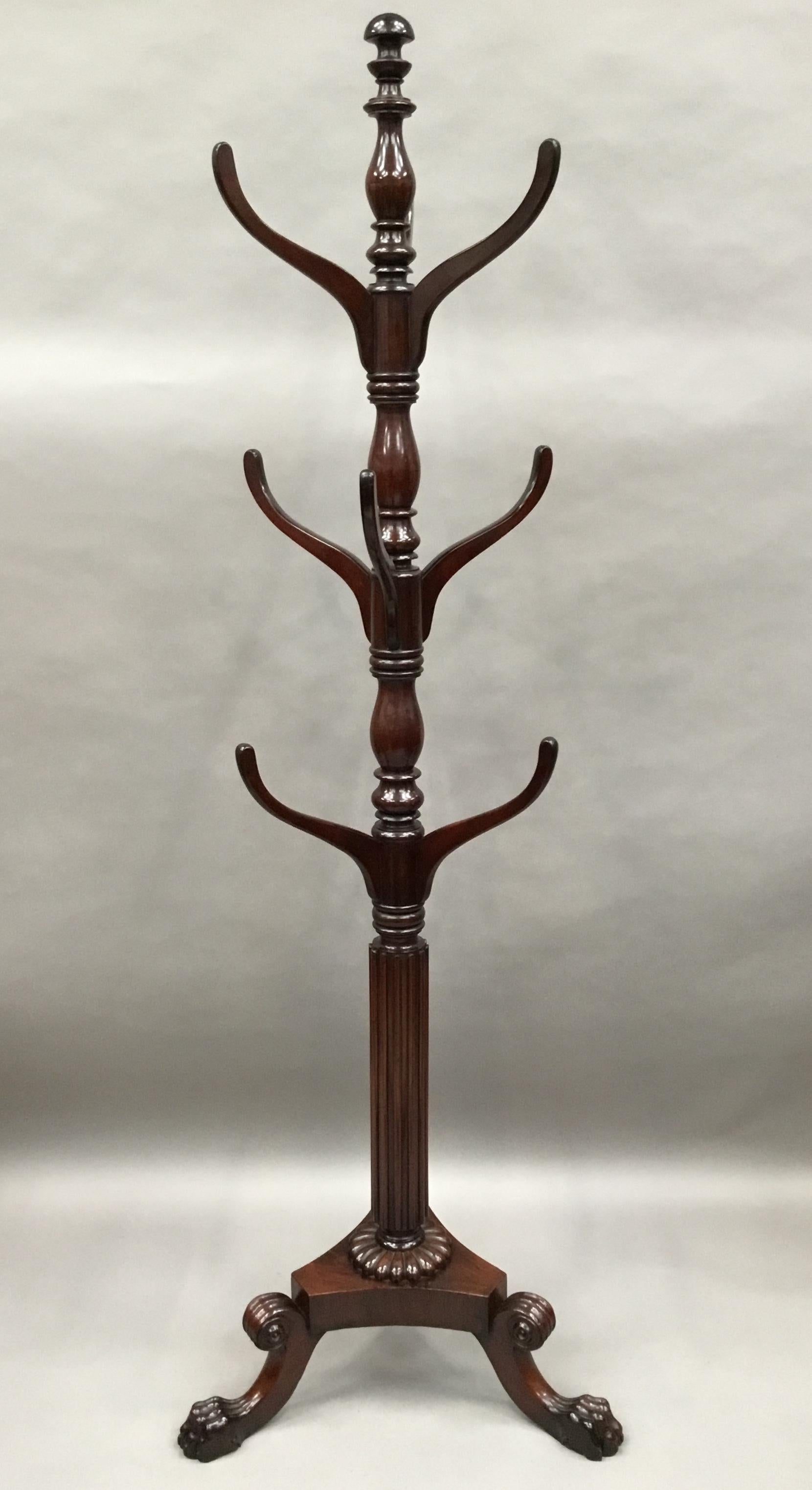 An impressive Regency mahogany hat and coat hall stand of large proportions; the central turned column with 9 shaped arms; terminating with a mushroom finial; below the arms the column having raised flutes finishing with a gadrooned moulding on a