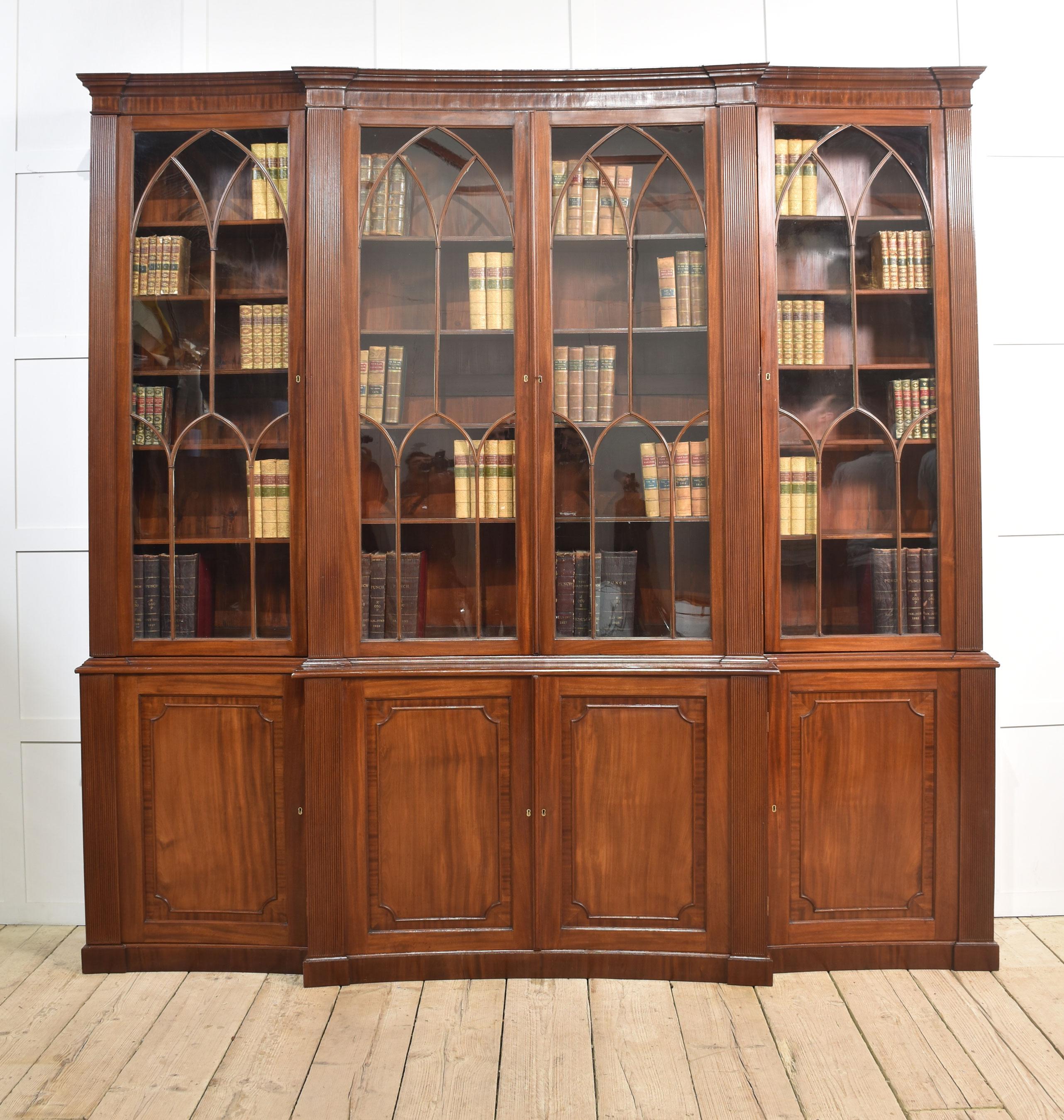 Libreria in mogano, con cornicione sagomato e concavato, che sovrasta quattro grandi ante curve a vetri astragali che si aprono per rivelare un interno a scaffali regolabili, fiancheggiato da colonne a gradini. La sezione di base è dotata di porte