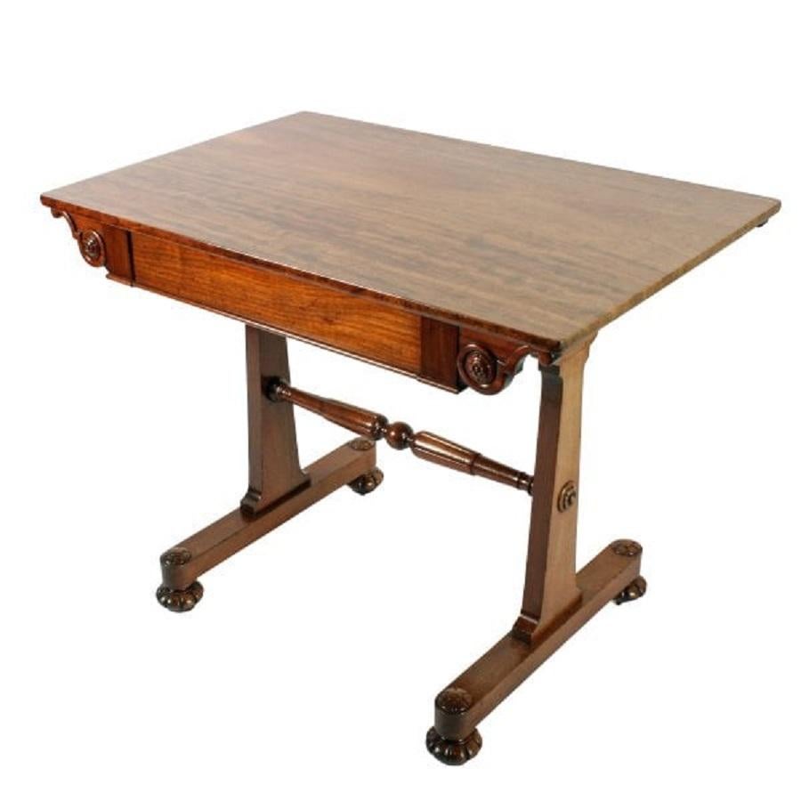 An early 19th century Regency mahogany one drawer library table.

The table has a pair of platform bases with carved bun feet and disguised casters.

The two tapering upright supports are joined by a turned and carved cross rails.

The oblong