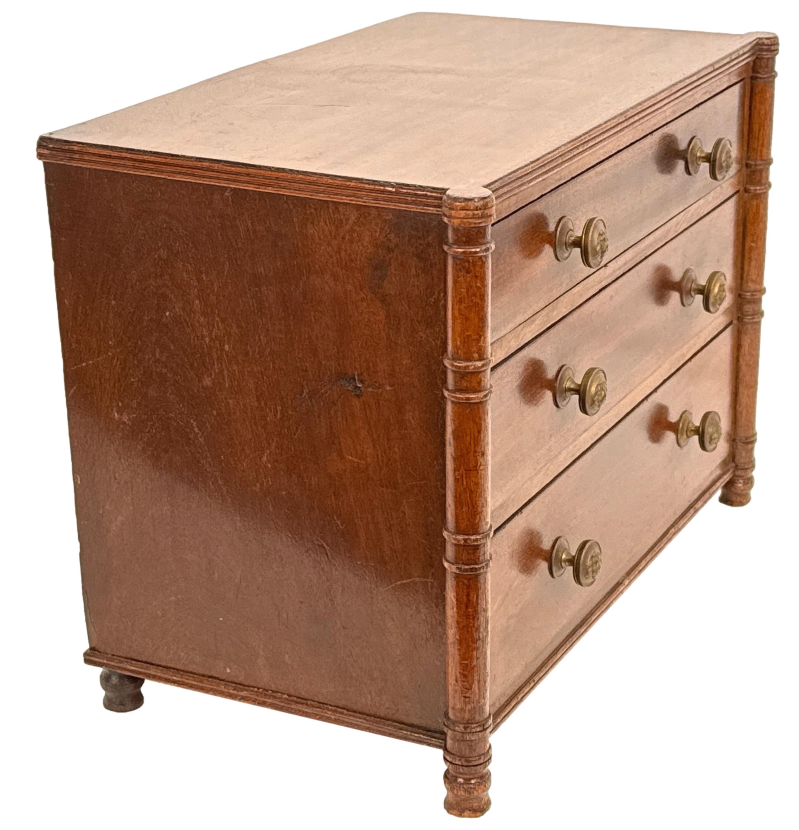 Una cassettiera in miniatura in mogano, di ottima qualità, risalente all'inizio del XIX secolo, periodo Regency, con un piano rettangolare ben strutturato e tre lunghi cassetti, con pomelli in ottone torniti di ricambio, affiancati da eleganti