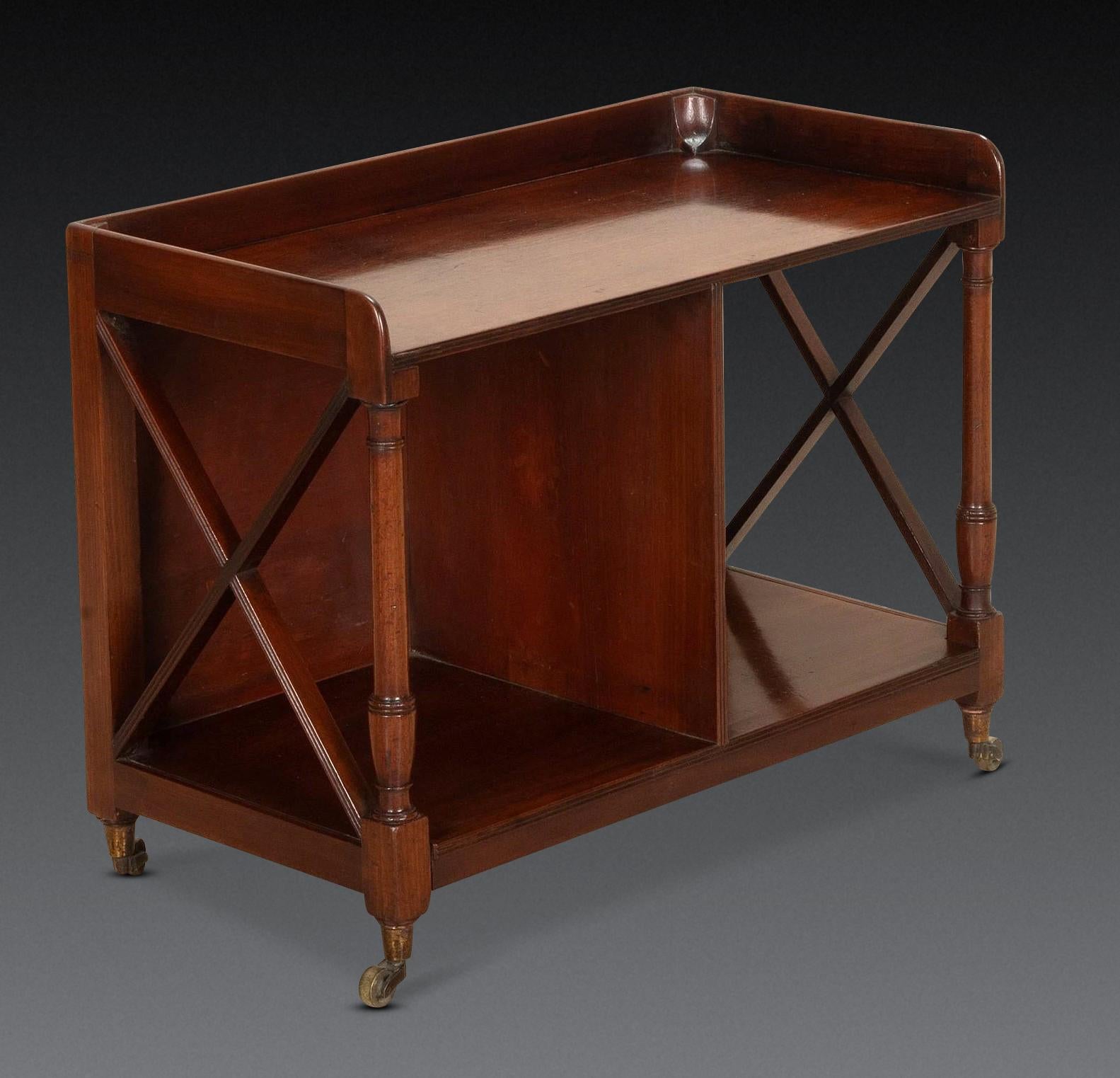 Un insolito tavolo occasionale/canterbury aperto in mogano della Reggenza, con galleria a tre quarti sopra i supporti torniti e le estremità a reticolo con ripiani a reticolo con divisione, sollevato su rotelle a tazza in ottone. Circa 1820. In