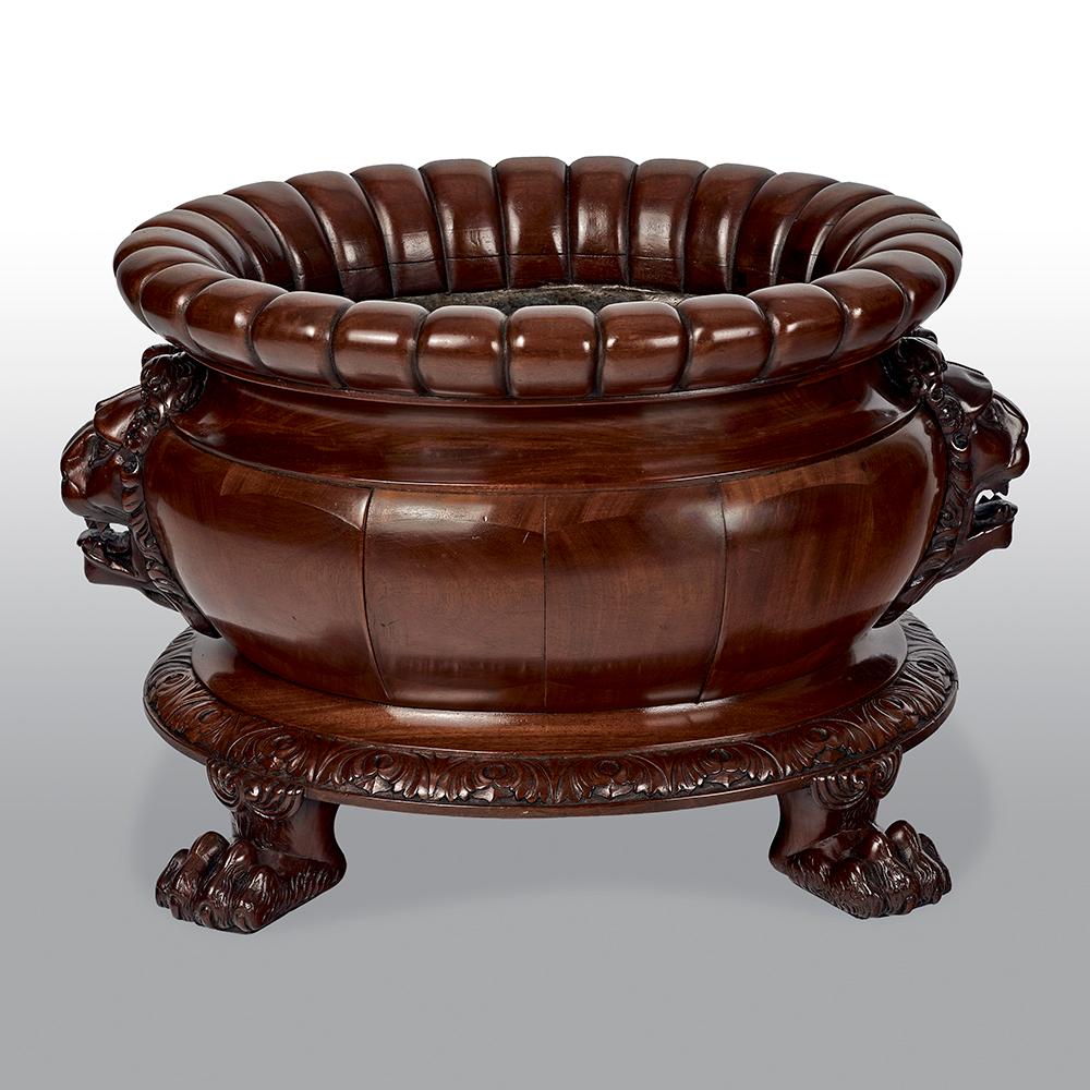 This impressive Regency mahogany oval wine cooler attributed to Gillows. The well carved gadrooning to the rim and flanked by superb lion mask handles, the oval body sits upon a well carved support with four well carved paw feet.

Footnote: A