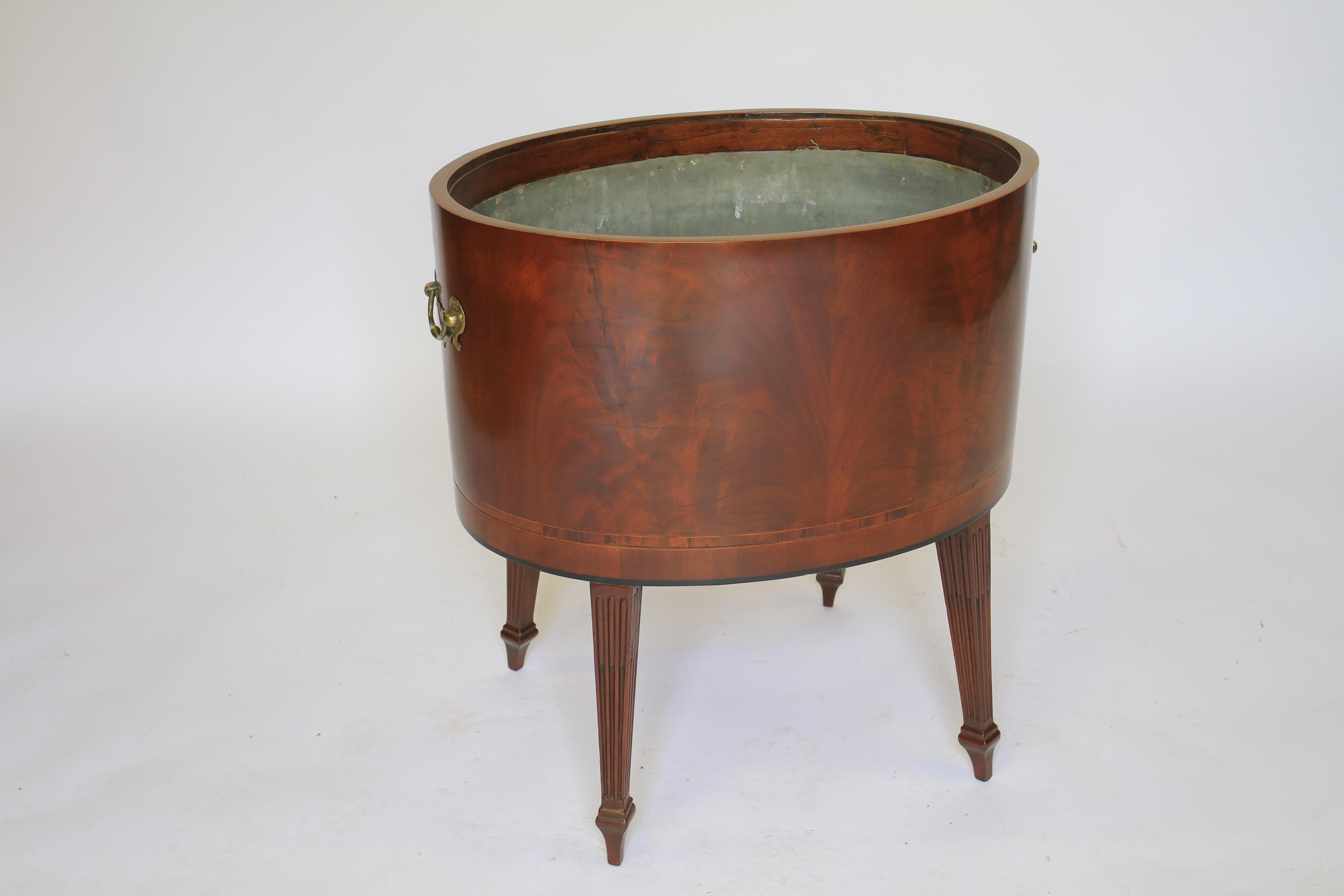 Regency Mahogany oval wine cooler
Open top,
Tinned interior inner Height :28cm
Figured mahogany with banded inlay
Pair Brass carry handles each side
Standing on 4 reeded tapering legs 
