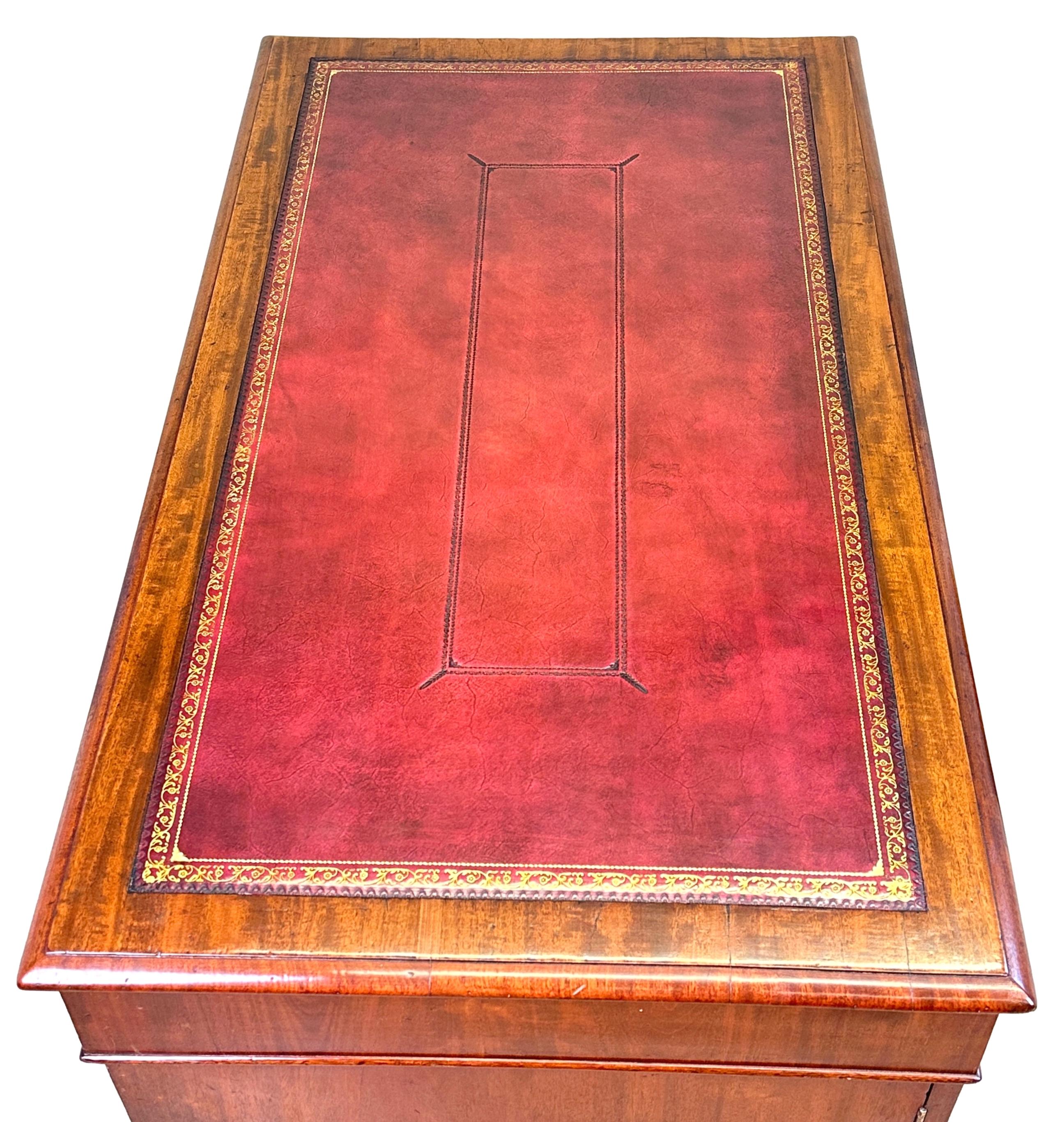 Scrivania a piedistallo in mogano di piccole proporzioni, di ottima qualità, risalente all'inizio del XIX secolo, periodo della Reggenza, con un attraente inserto in pelle lavorata dorata sul piano a fasce incrociate, oltre nove cassetti sul davanti
