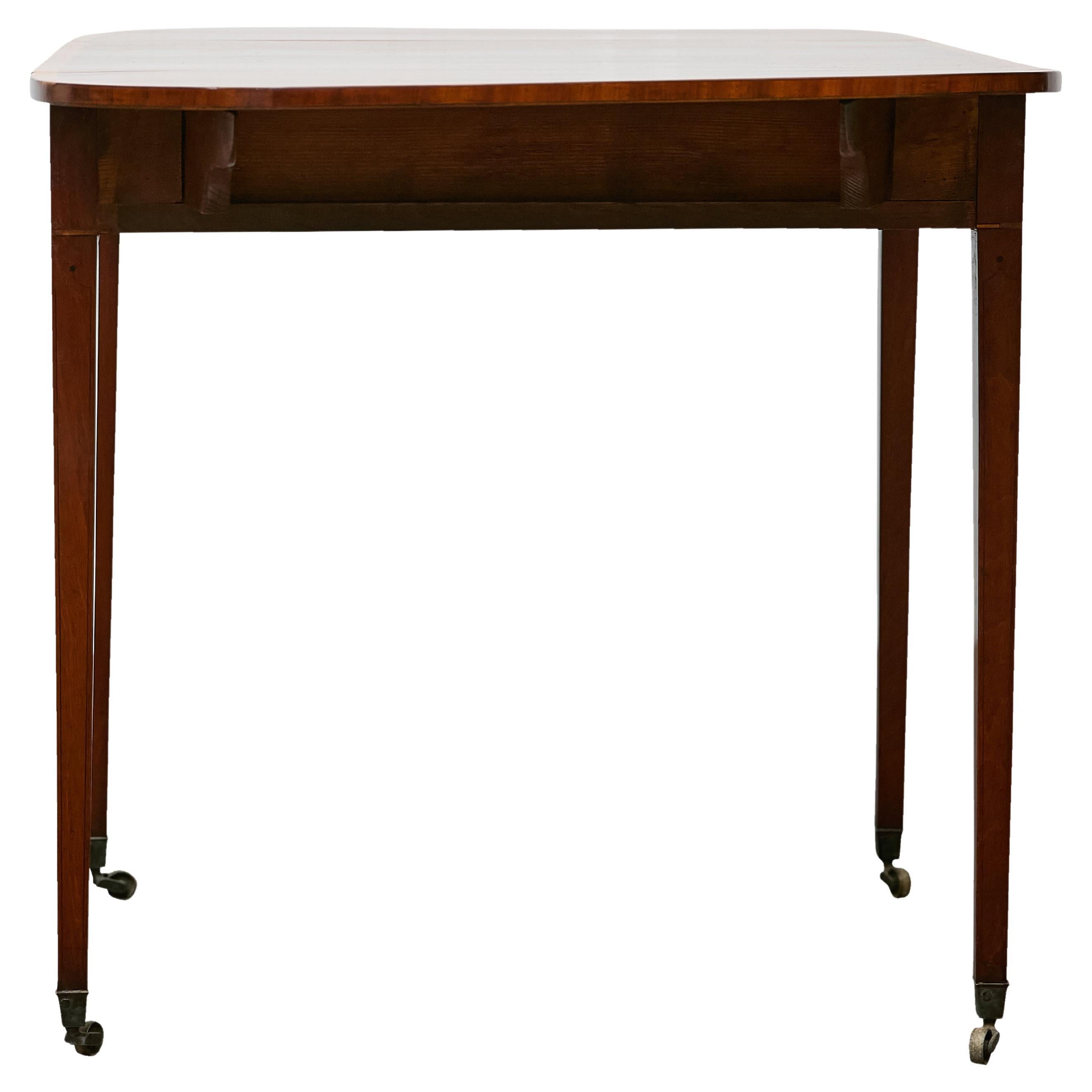 Crafted in England in the early 19th century, this Regency Pembroke table presents a refined balance of form and function. Constructed from mahogany with a warm, lustrous patina, the table features a rectangular top with rounded drop leaves,
