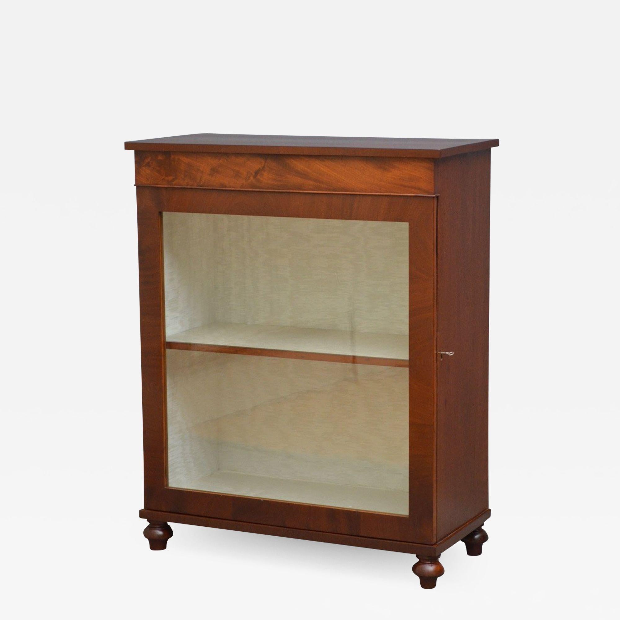 Sn4172, Regency pier cabinet in mahogany, having flamed mahogany top with crossbanded edge above figured frieze and a glazed door enclosing a shelf, all standing on original turned feet. This display cabinet has been sympathetically restored and is